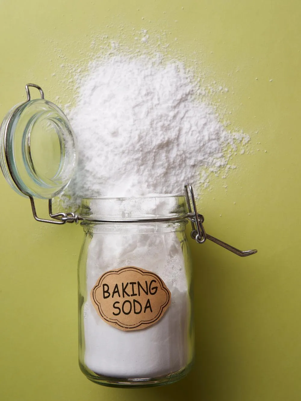 a jar labeled baking soda spilled on a green background