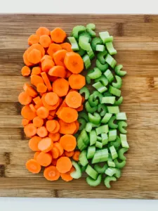 a cutting board with chopped carrots and celery