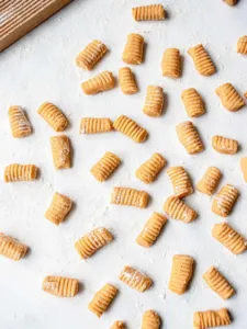 pieces of cut and floured sweet potato gnocci set out on a floured surface