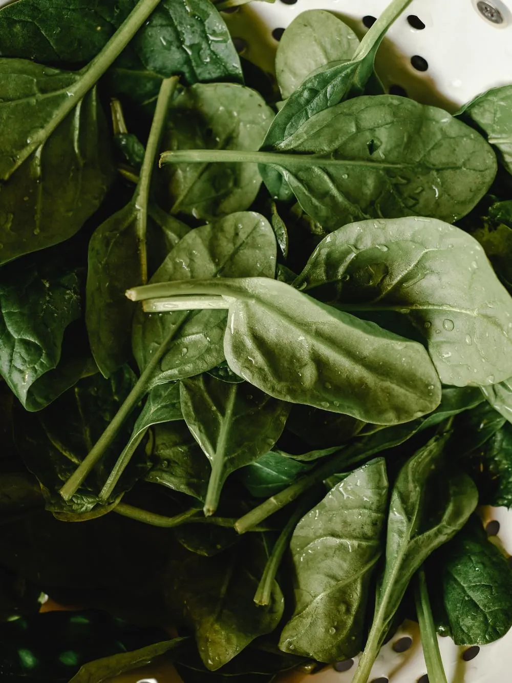 a colander full of freshly rinsed spinach