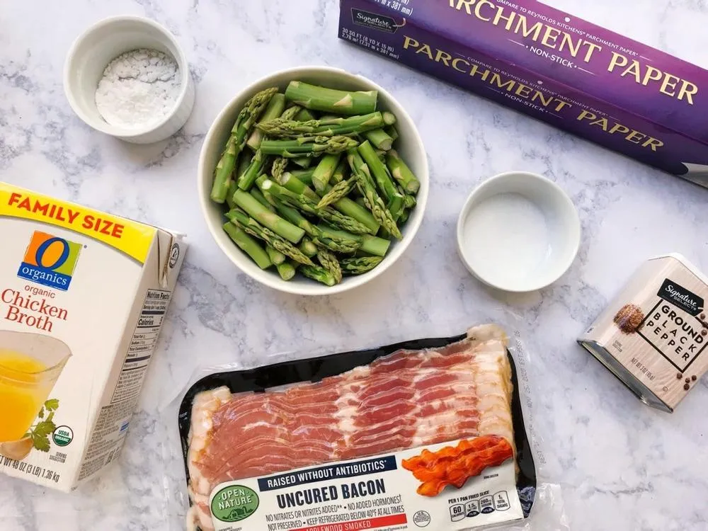 Product layout: bowl of asparagus, small bowl of salt, small bowl of potato starch, chicken broth, bacon, black pepper, and parchment paper