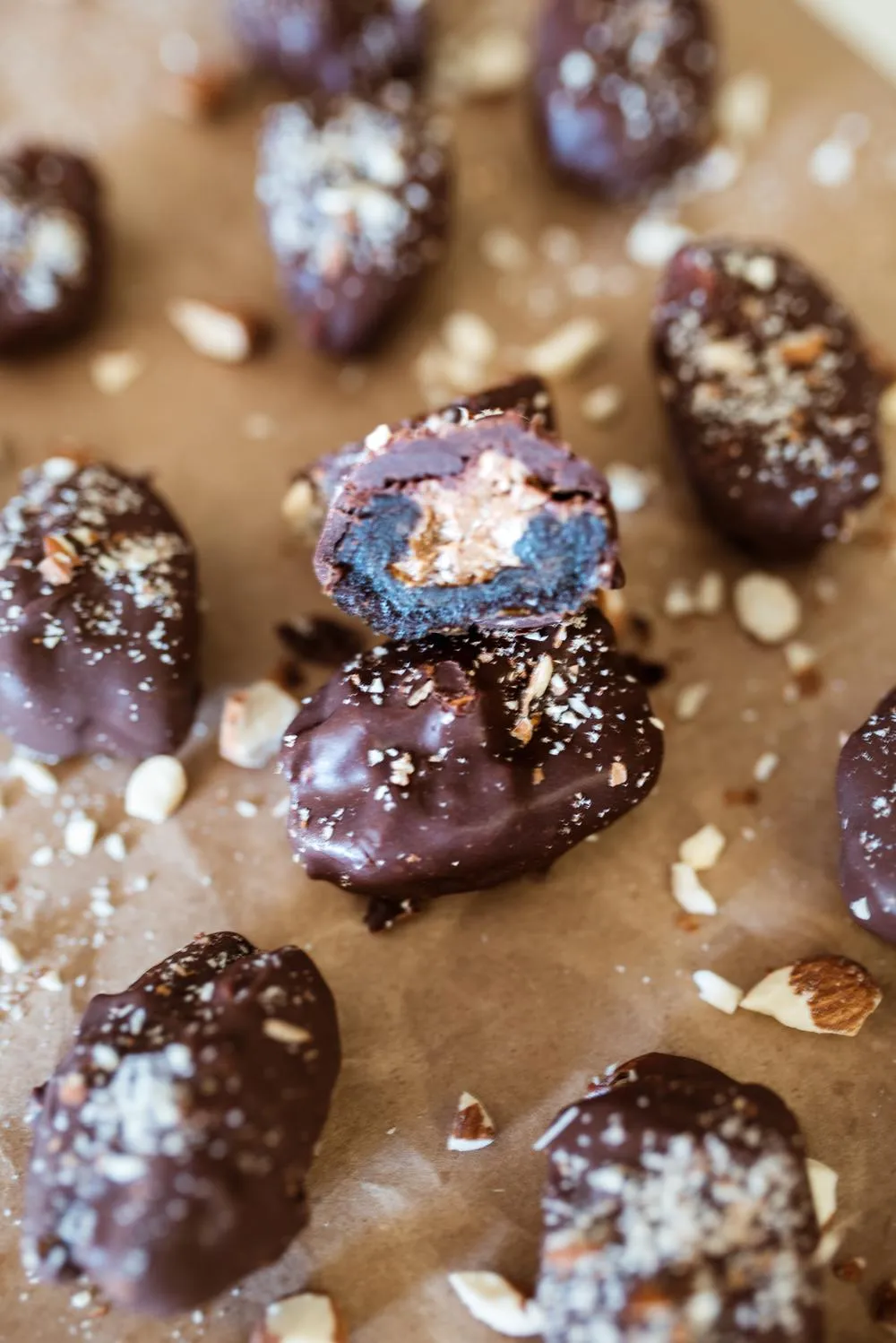almond butter stuffed dates lined up on brown paper and sprinkled with crushed almonds