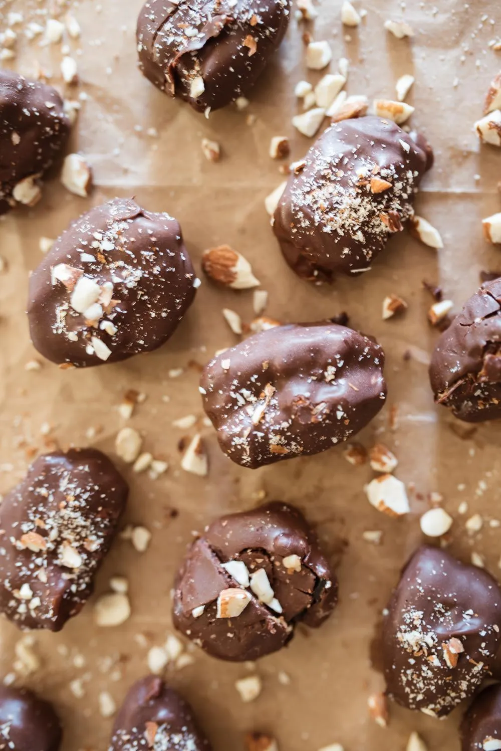 gut healing almond butter healthy date snickers layed out on brown paper and sprinkled with crushed almonds
