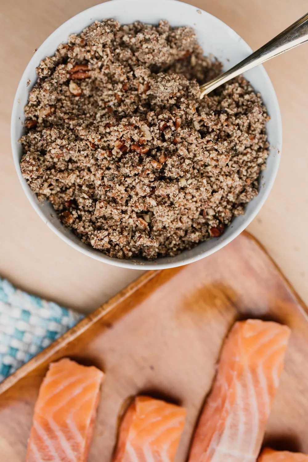 a white bowl of toasted pecan crumble, which is a mixture of toasted pecans, honey, coconut oil, salt and herbs de provence