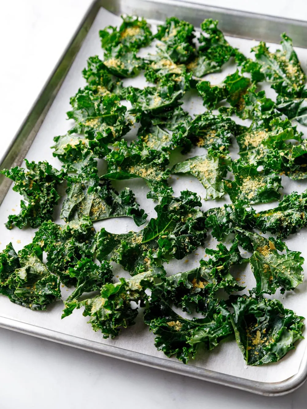 a baking sheet of kale sprinkled with seasonings
