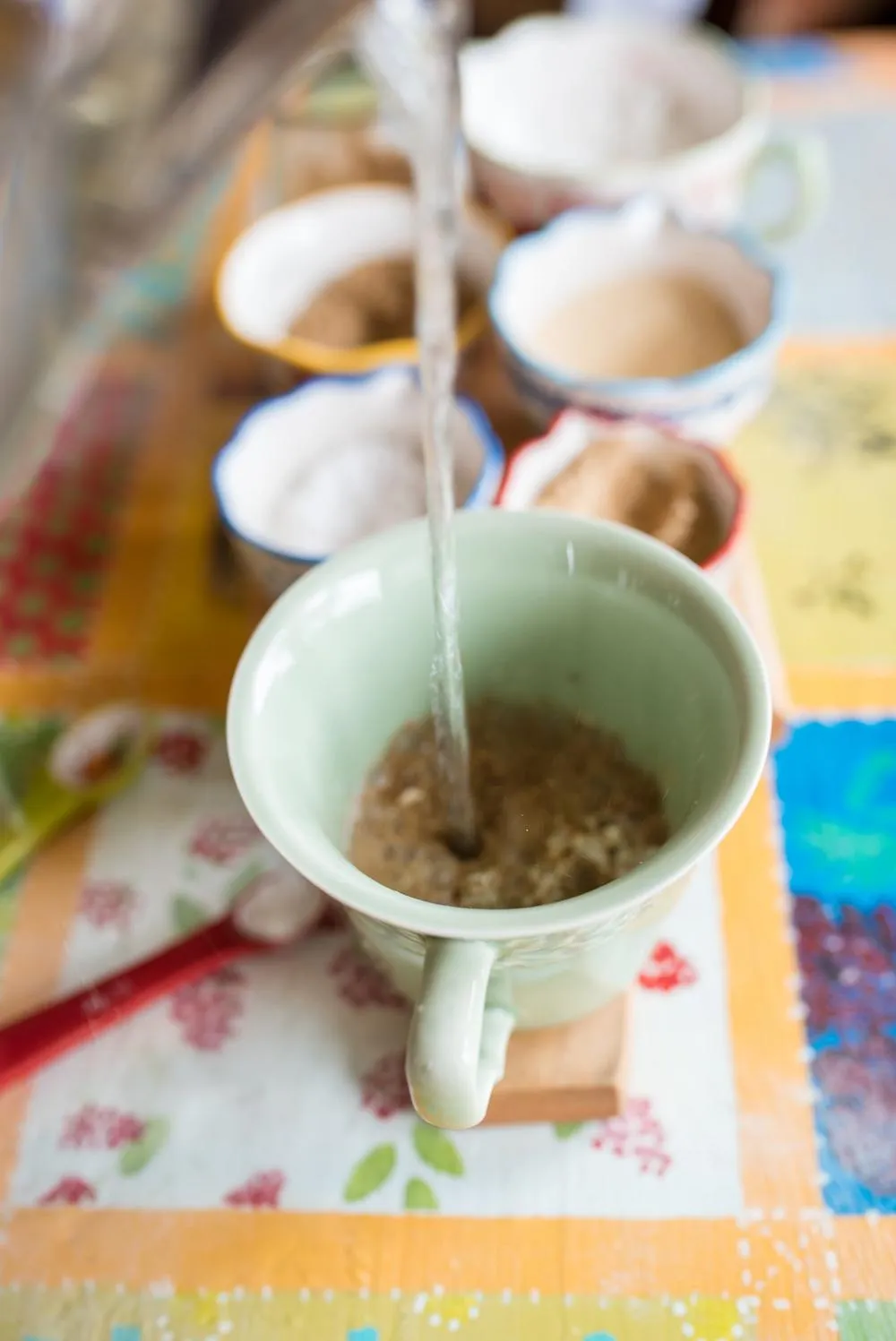 water is being poured into a green mug of heartburn ginger tea
