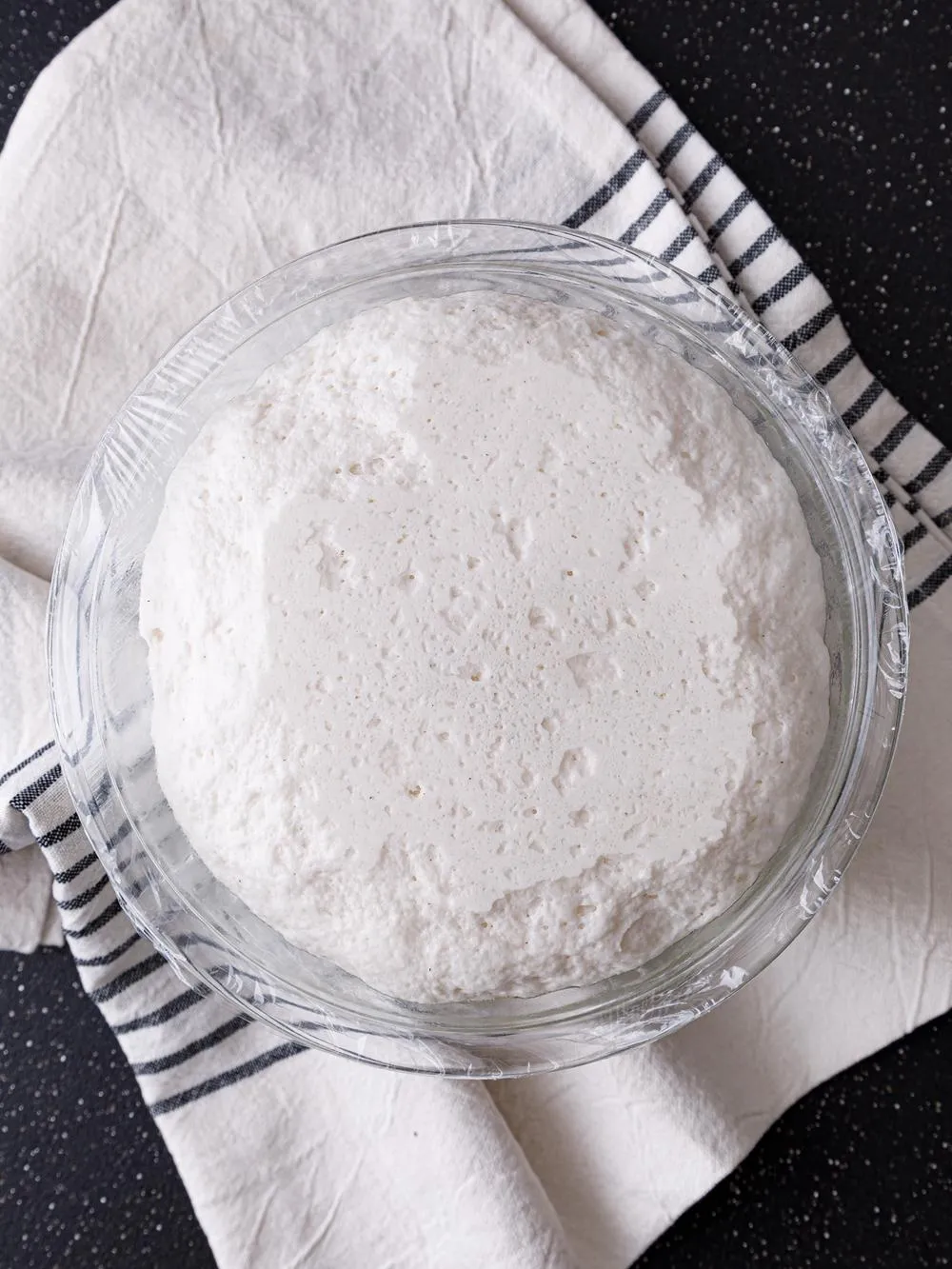 a bowl of risen gluten free pizza crust on a tea towel
