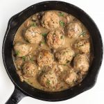 A cast iron skillet full of turkey meatballs and mushroom gravy