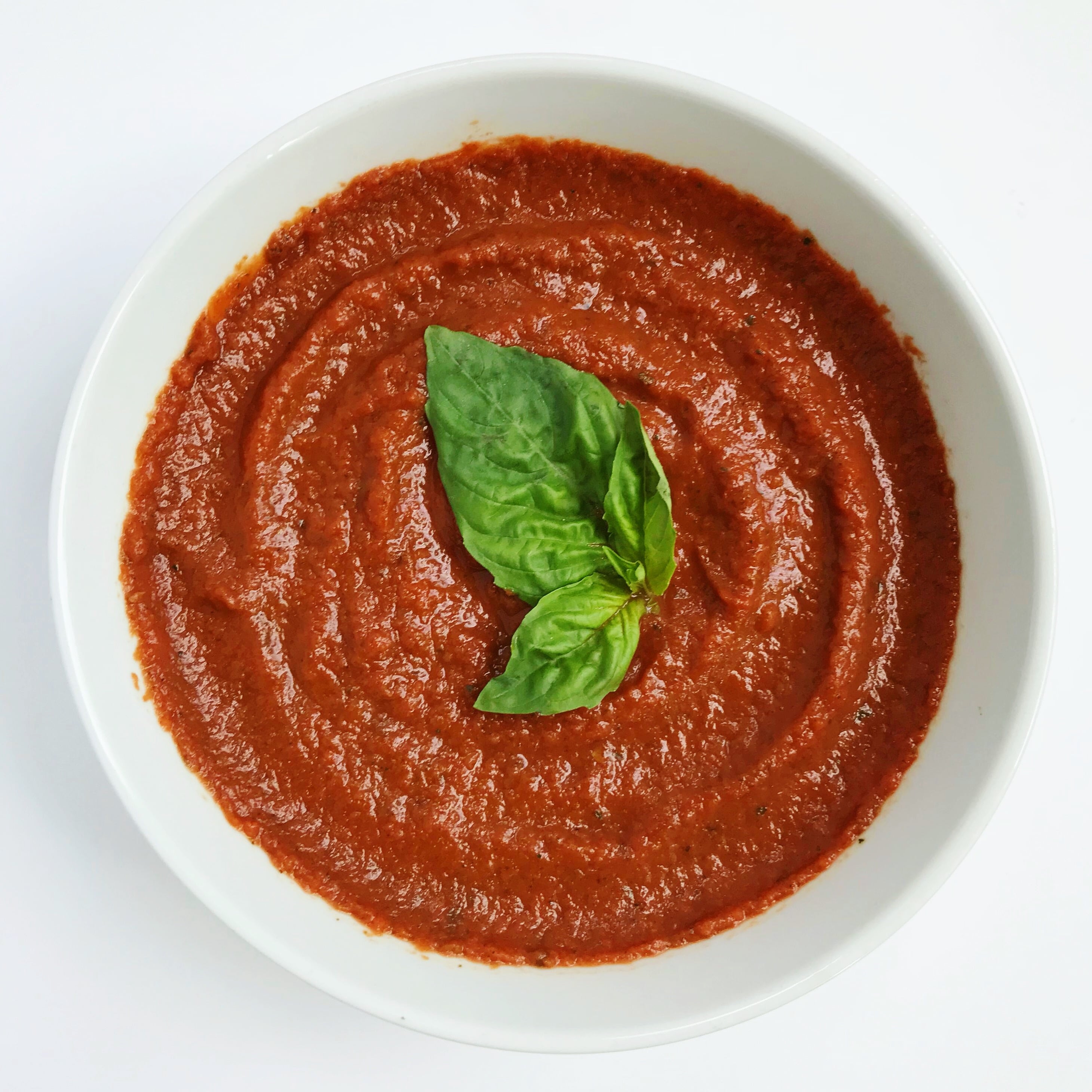 Bowl of tomatoless sauce topped with fresh basil leaves