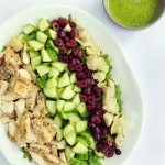 arugula chopped salad topped with artichoke hearts, olives, chicken, cucumbers, and a side of basil dressing