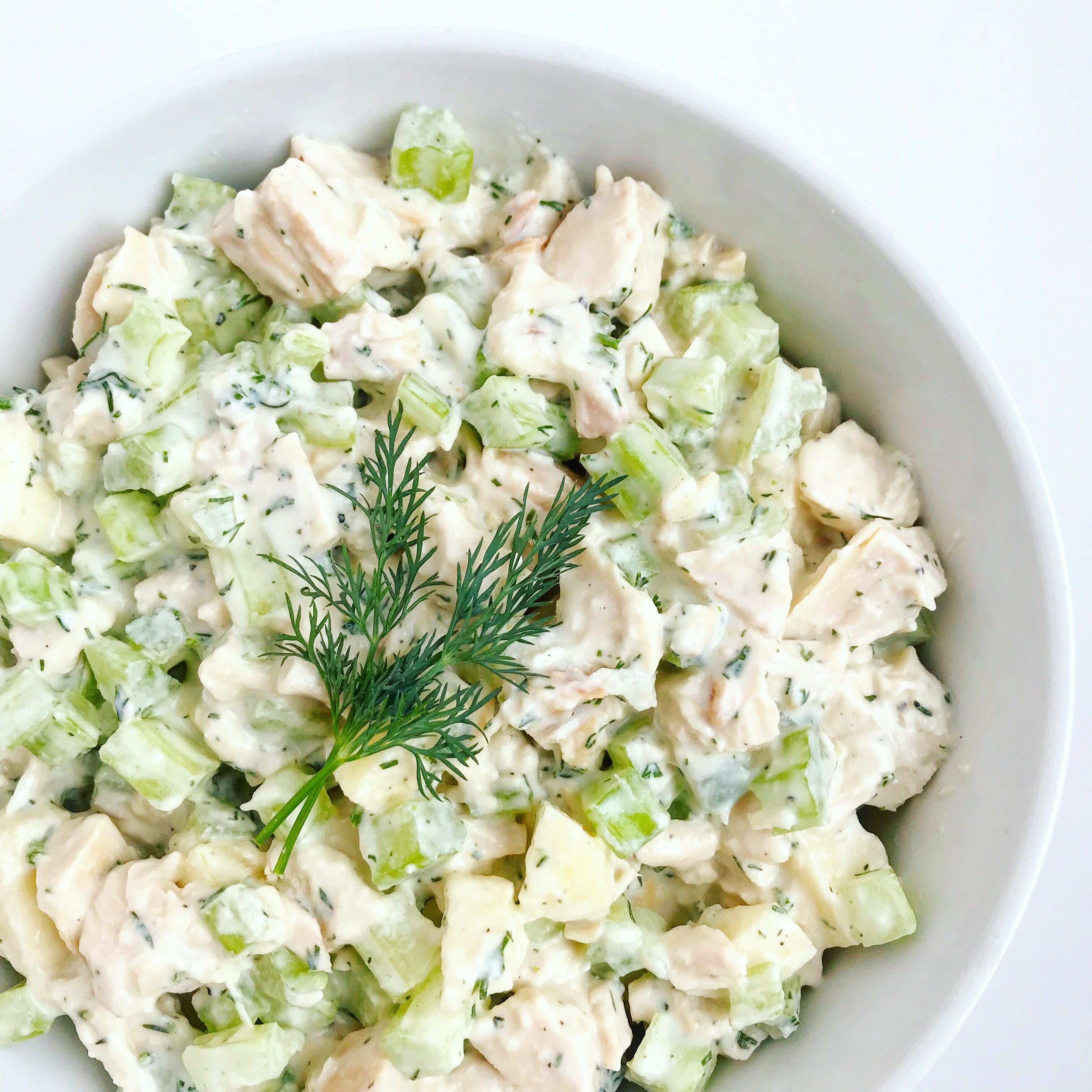 A bowl of dairy-free chicken salad, topped with fresh dill.