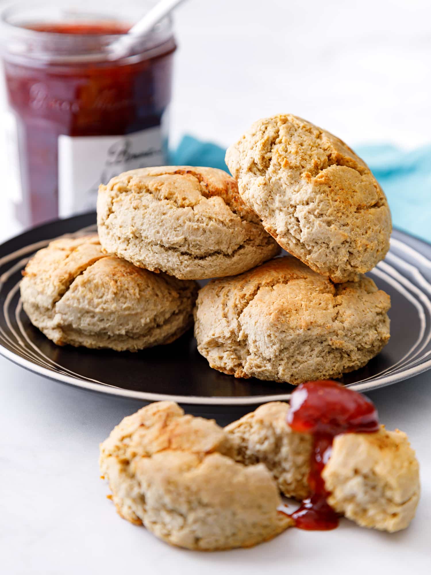 plate with oat flour biscuits and one on the table split in two with strawberry jam