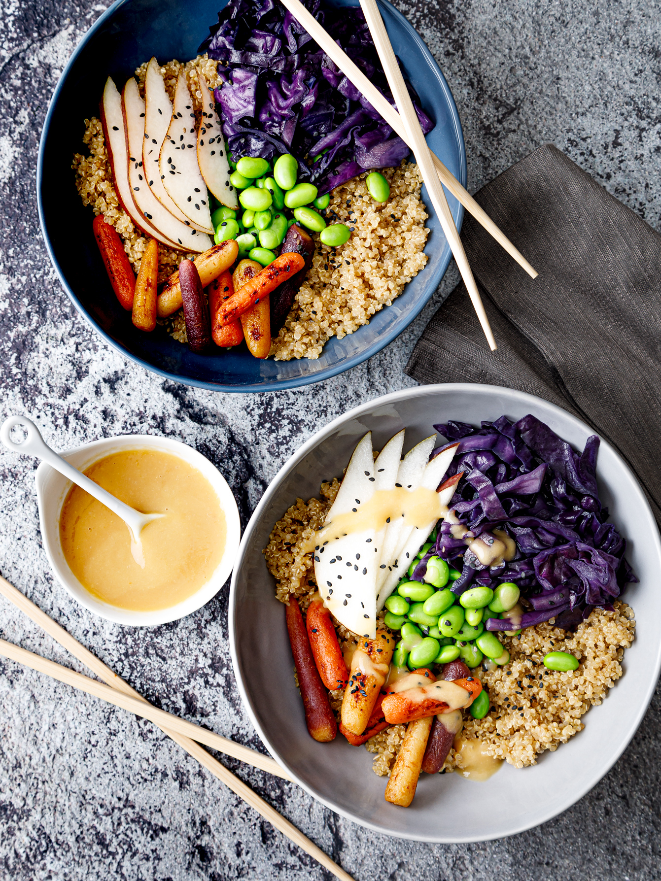 Two bowls filled with colorful ingredients sit on a marble table