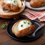 baked potato on a black plate cut open with a dollop of herbed ricotta. A delicous acid reflux friendly dish
