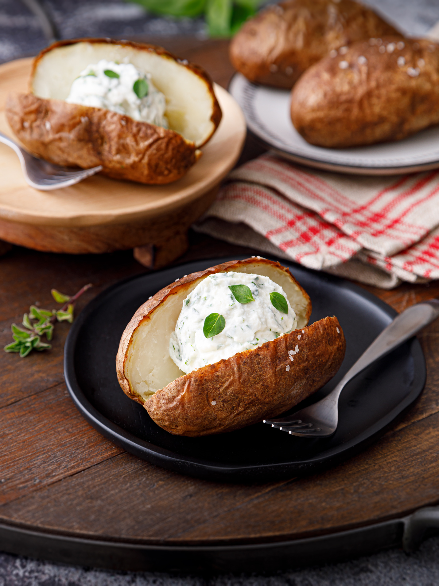 baked potato on a black plate cut open with a dollop of herbed ricotta. A delicous acid reflux friendly dish