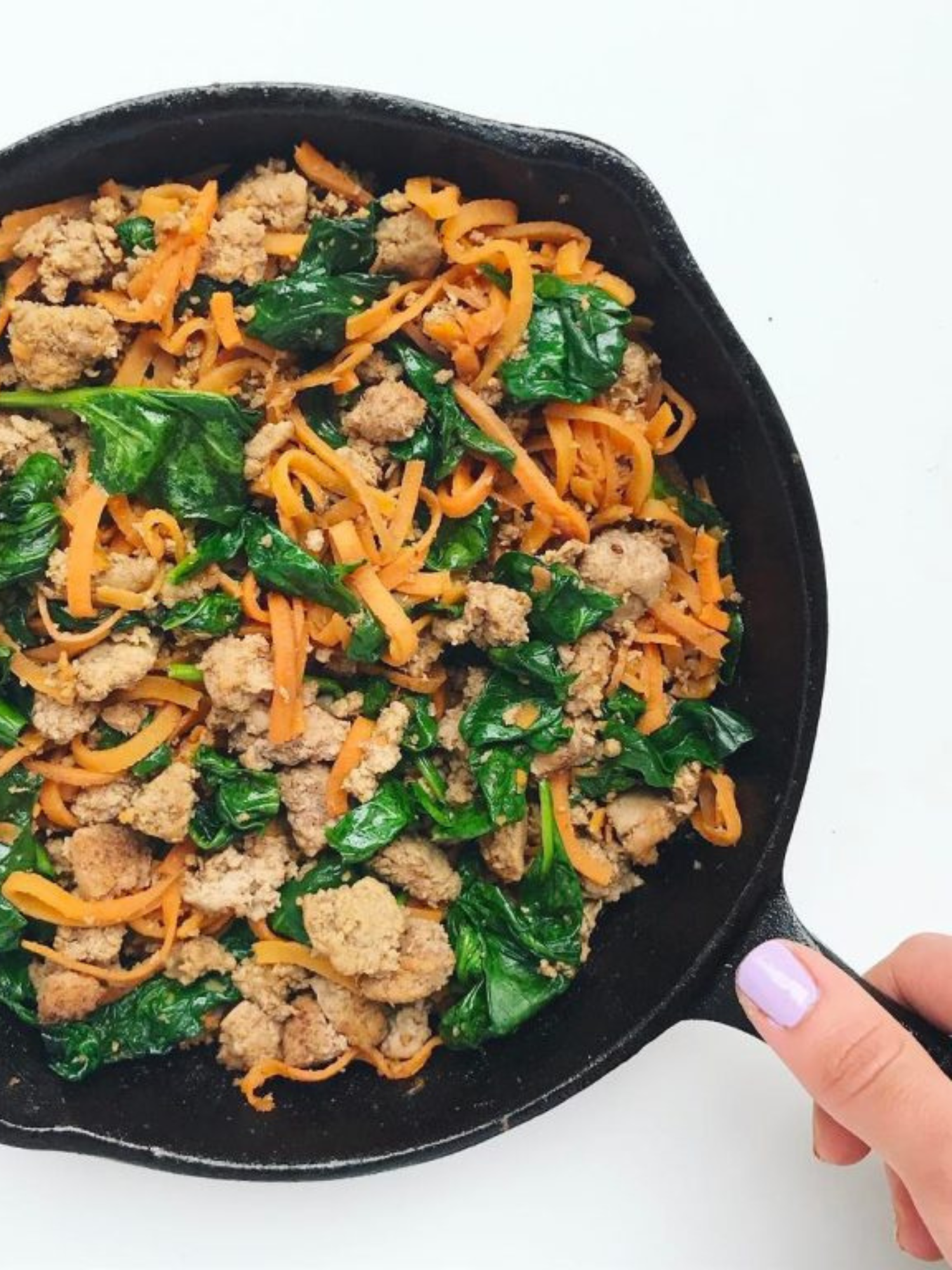 A cast iron skillet of sweet potato noodles, ground turkey and spinach