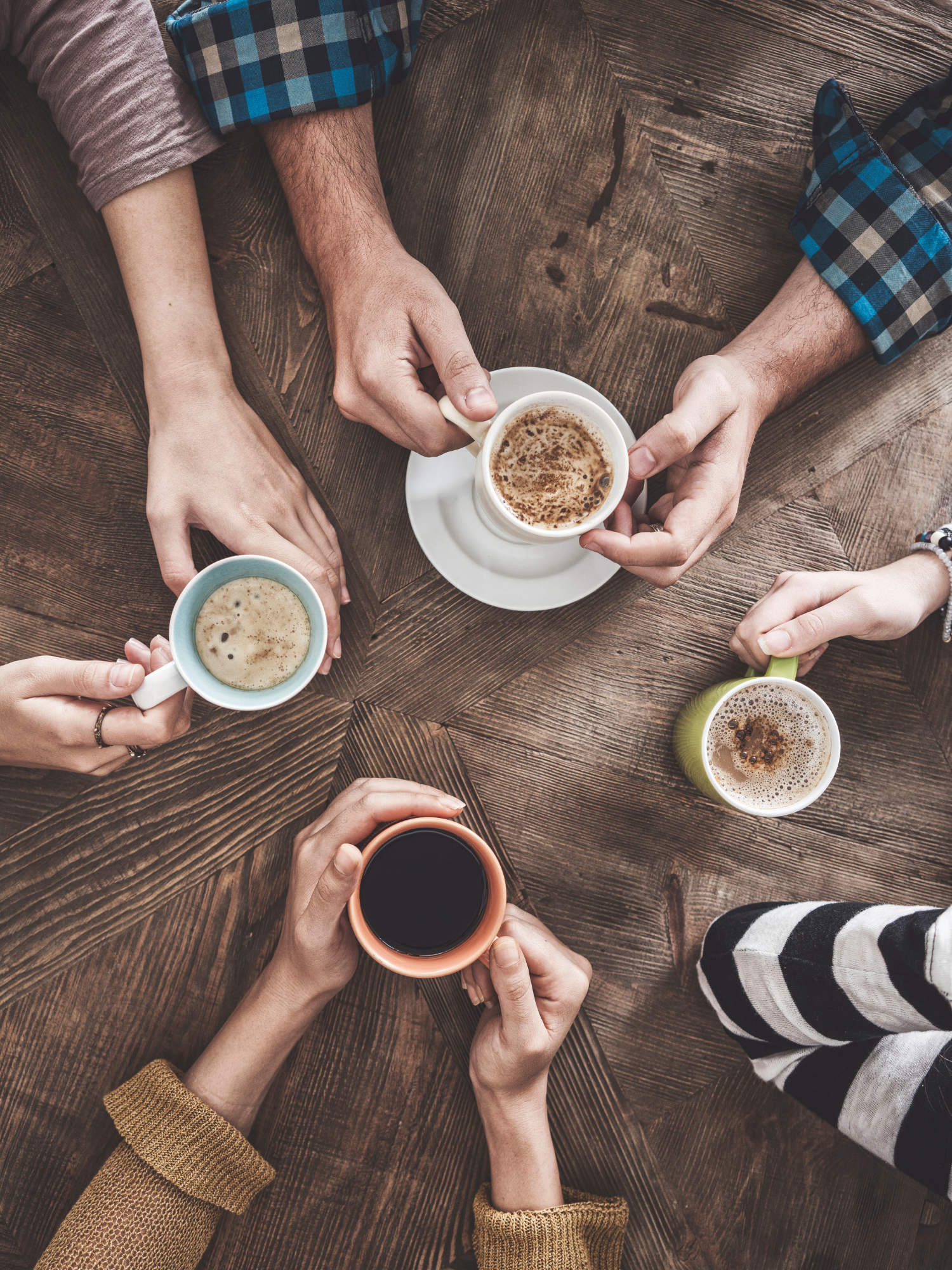 overhead image of four people holding coffee cups