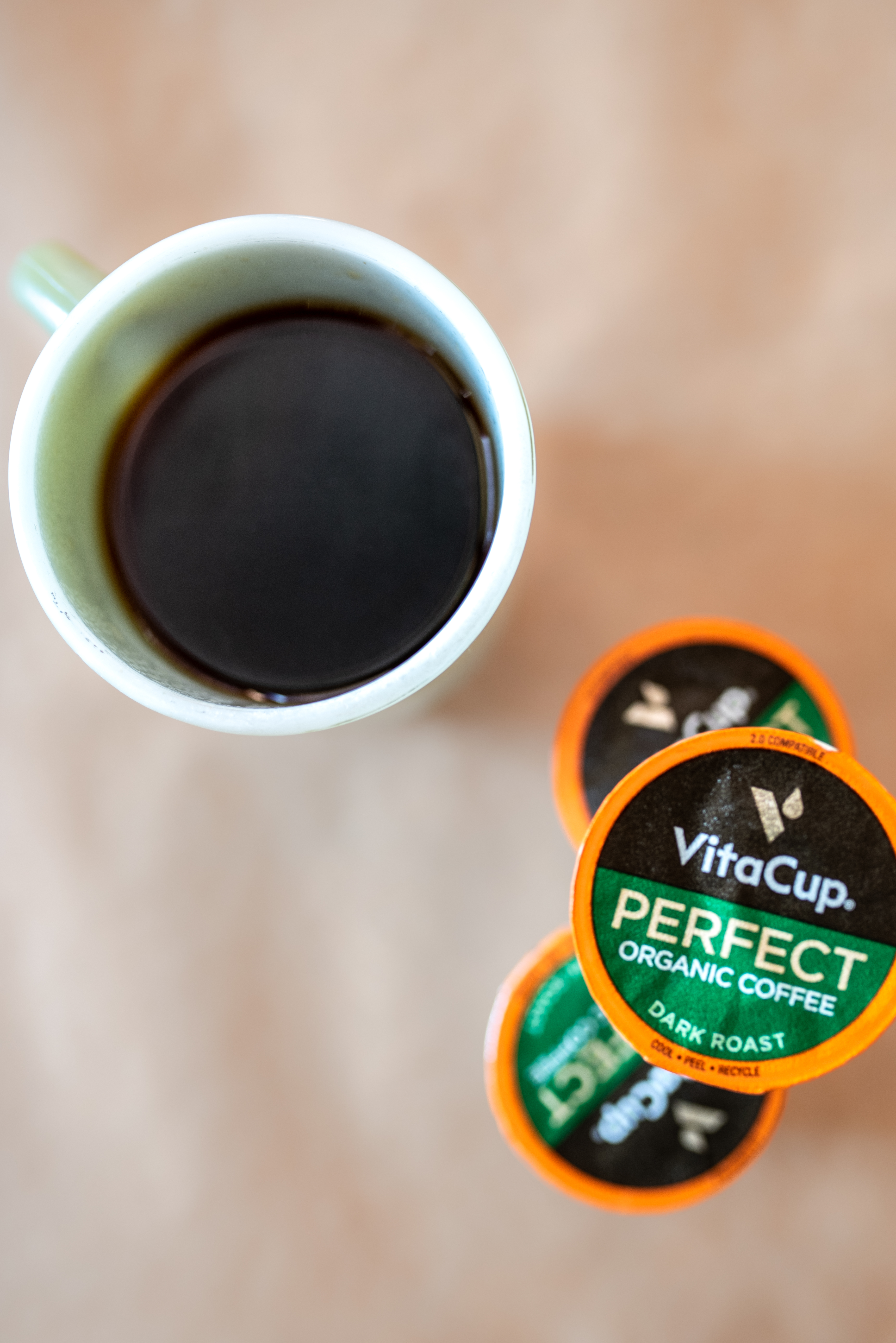 a green cup filled with coffee sitting on a brown table 