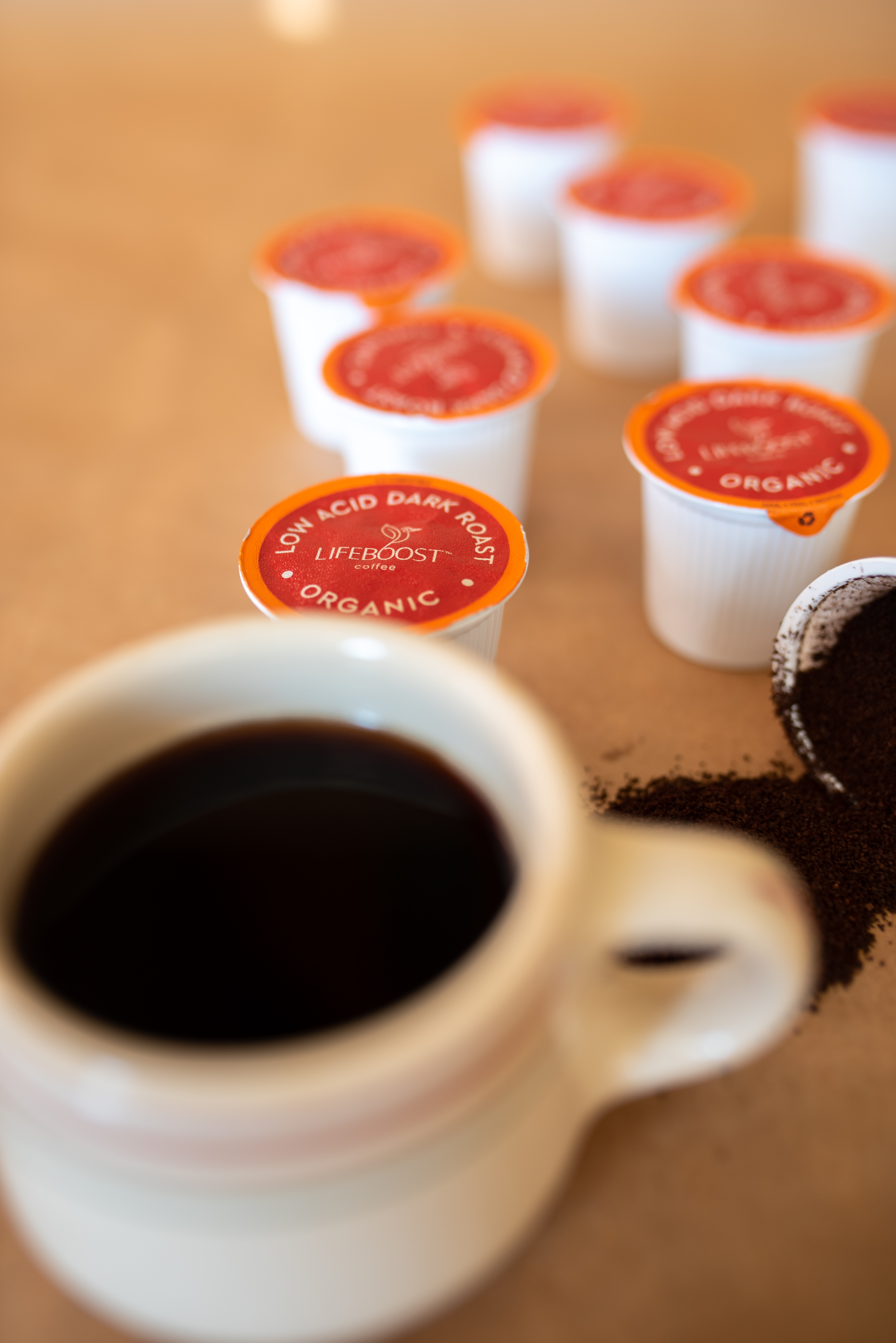 a white mug filled with coffee sitting next to red pods