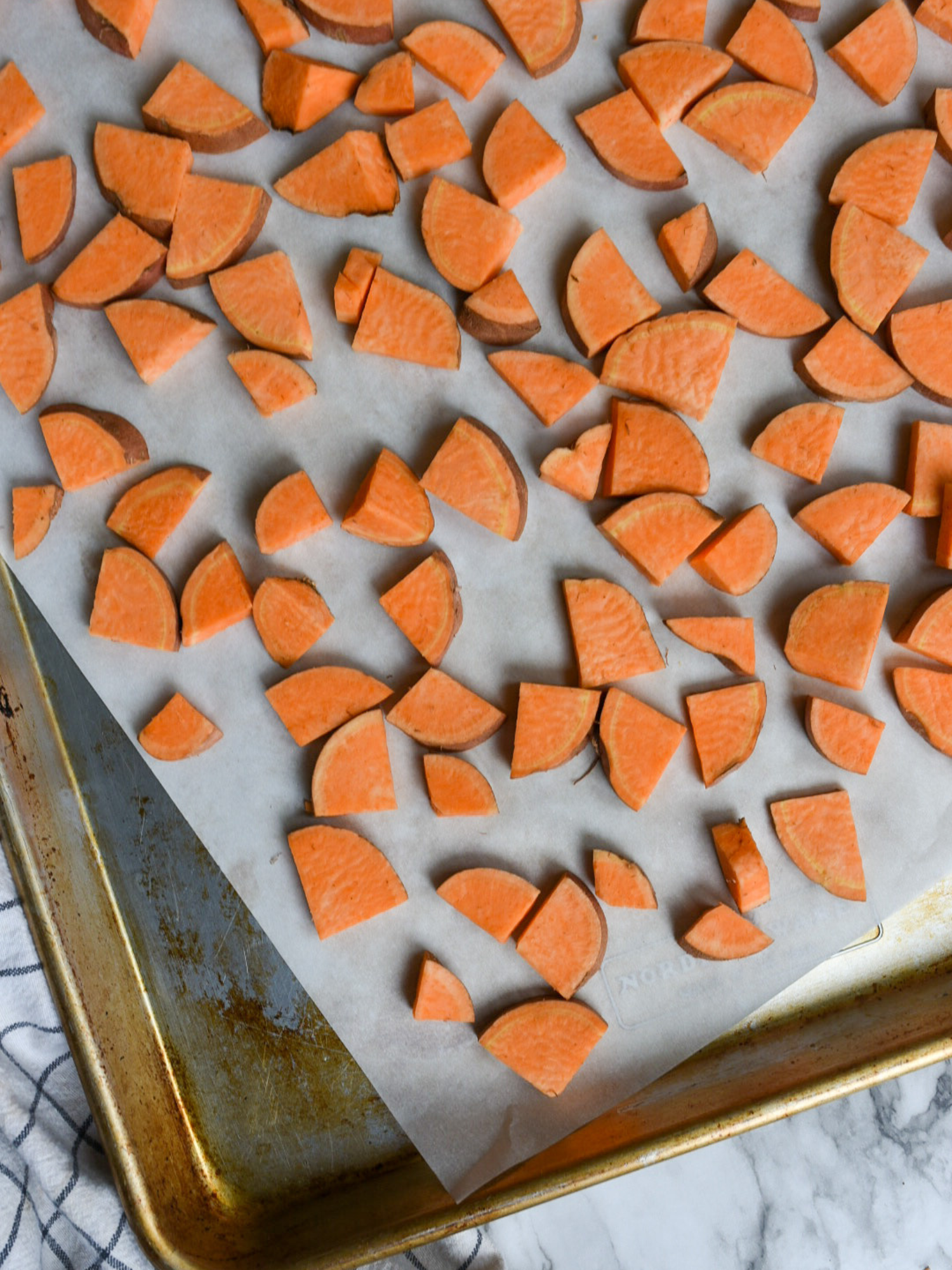 chopped sweet potatoes spread evenly on a parchment lined baking sheet