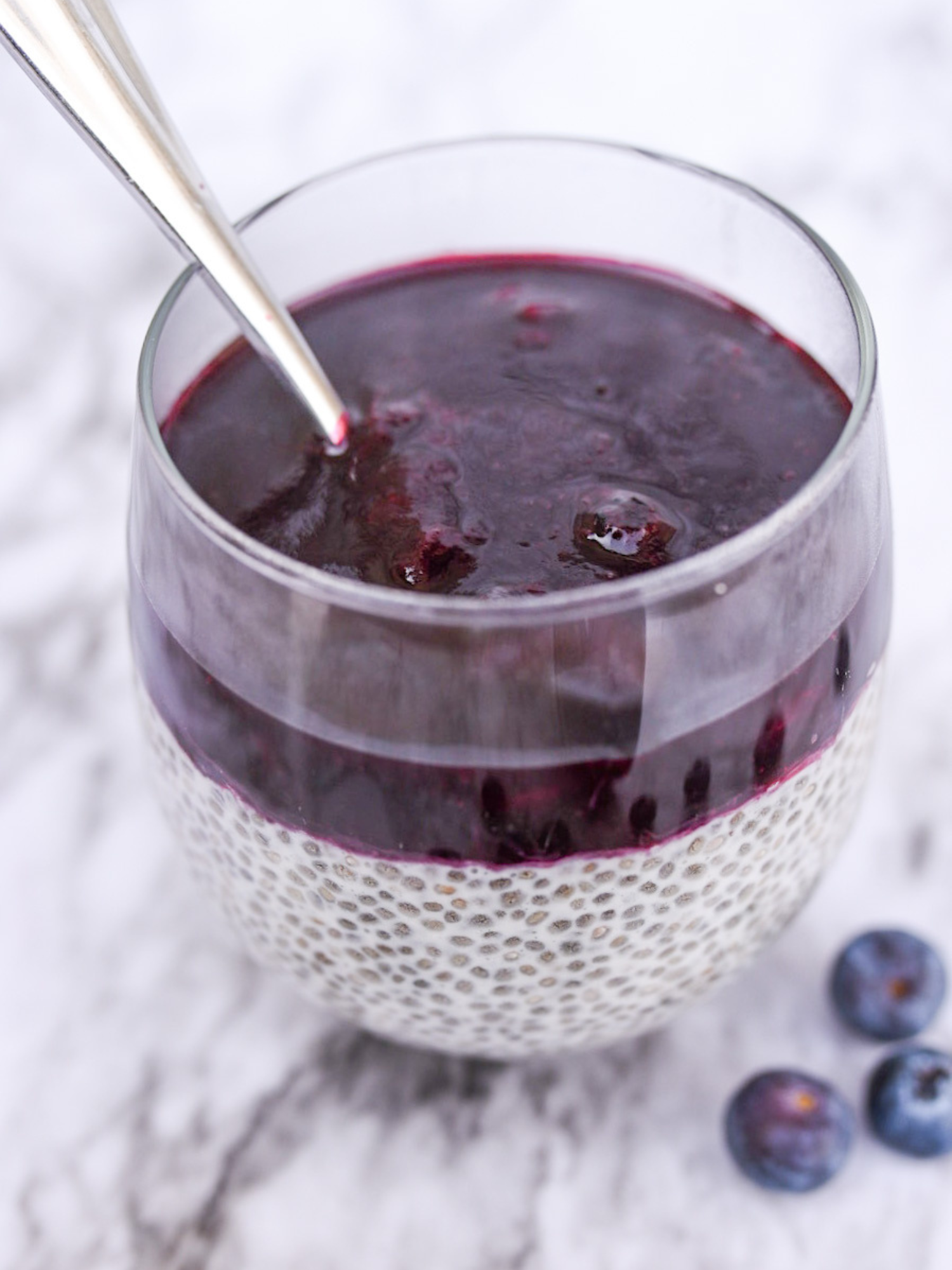 a cup of blueberry chia seed pudding on a marble tabletop