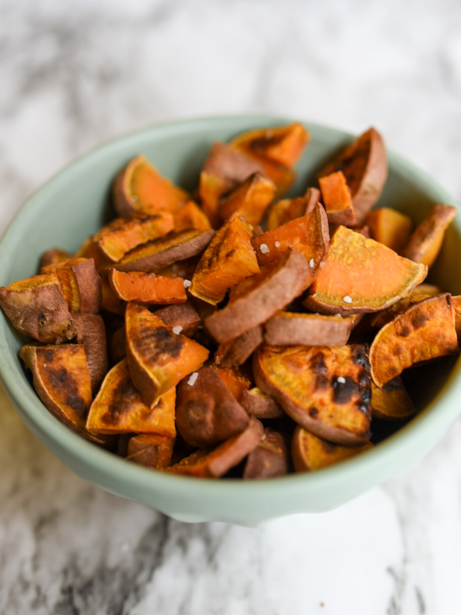 Oil Free Roasted Sweet Potatoes in a blue bowl on a marble countertop
