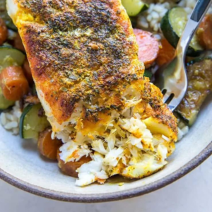 a bowl of jasmine, roasted vegetables and a piece of baked cod