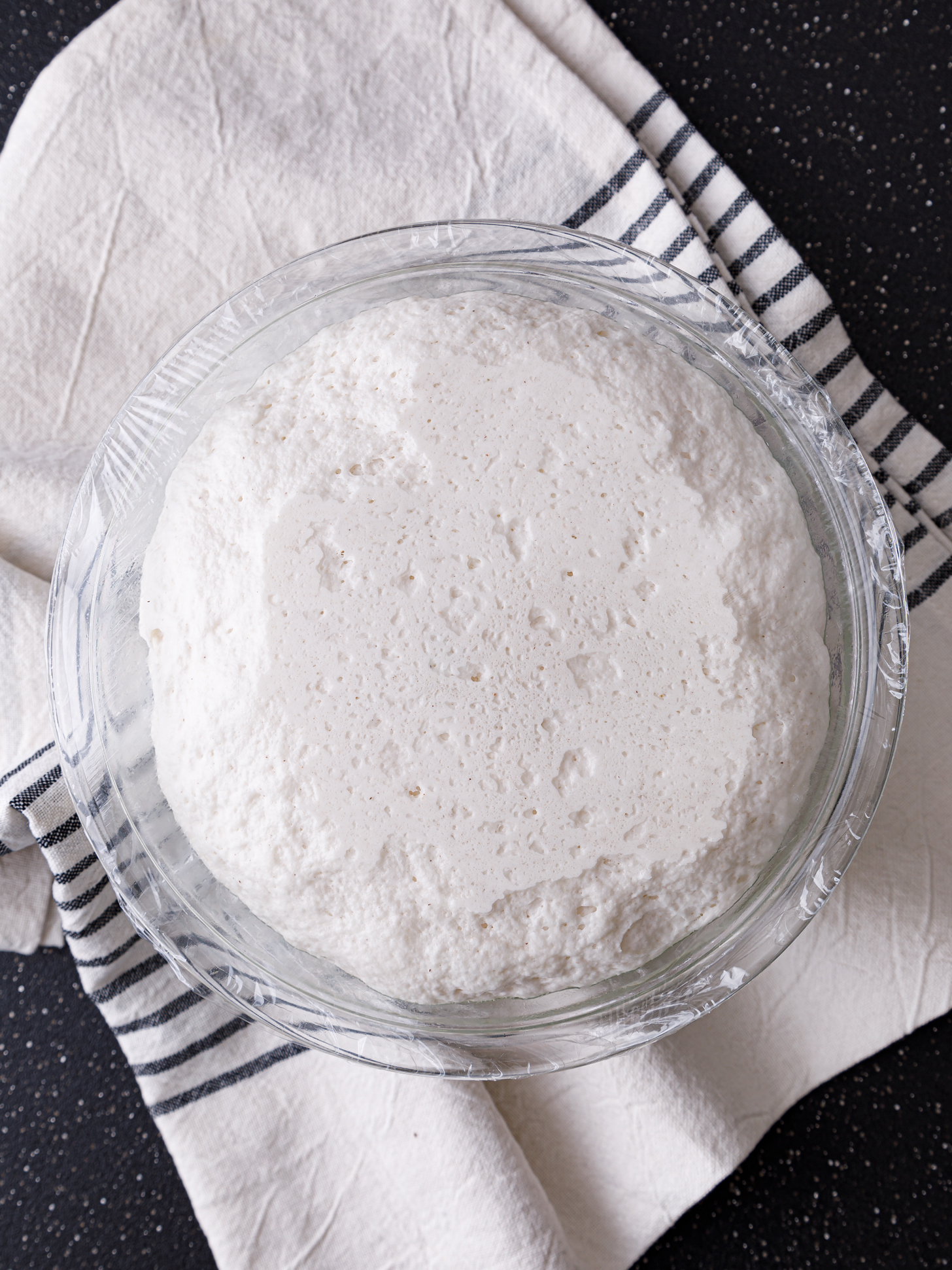 a bowl of risen gluten free pizza crust on a tea towel