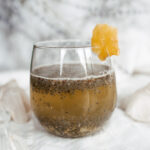 a glass with brownish liquid and garnish on a marble backdrop