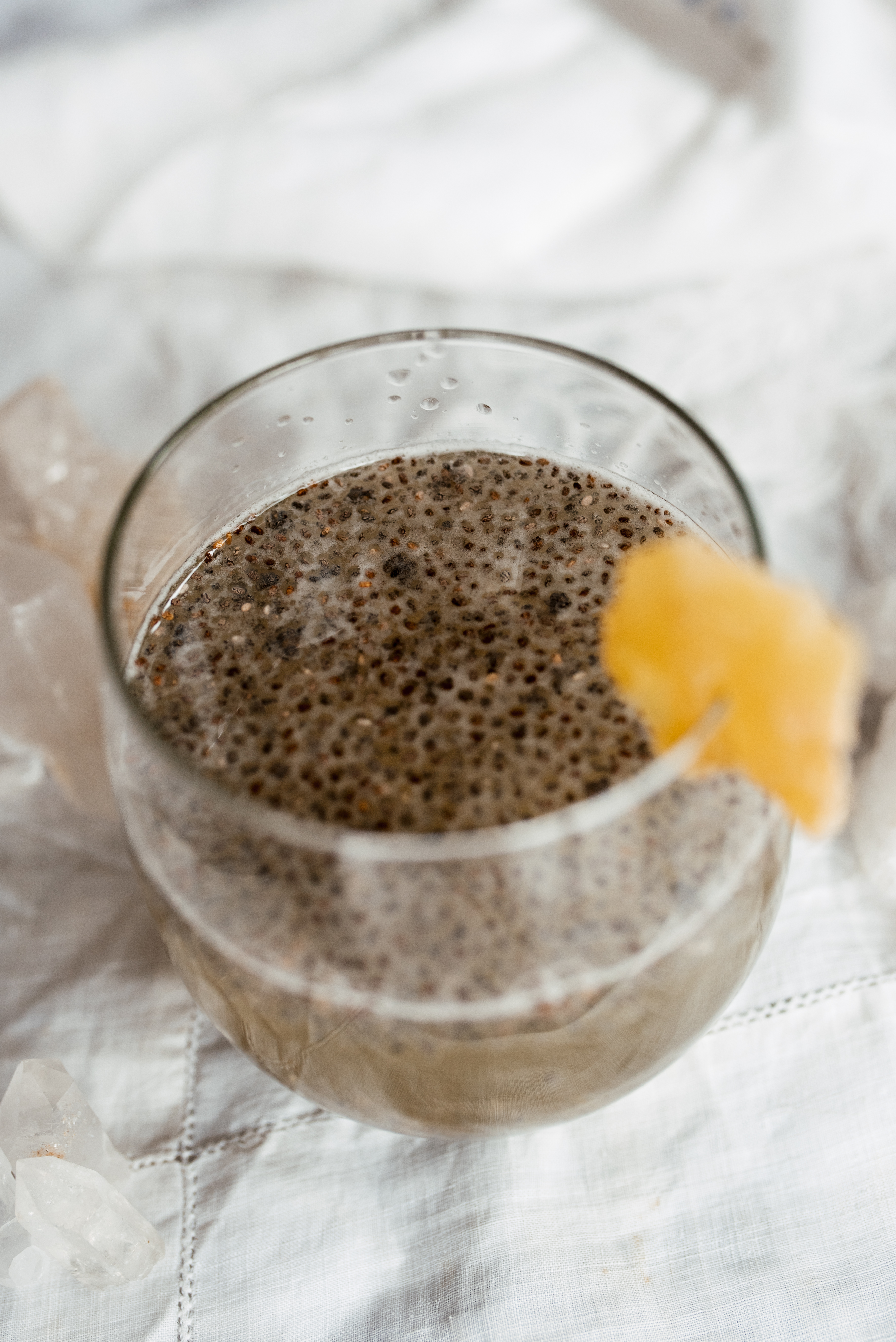 a glass with liquid and small black seeds sits on a marble table