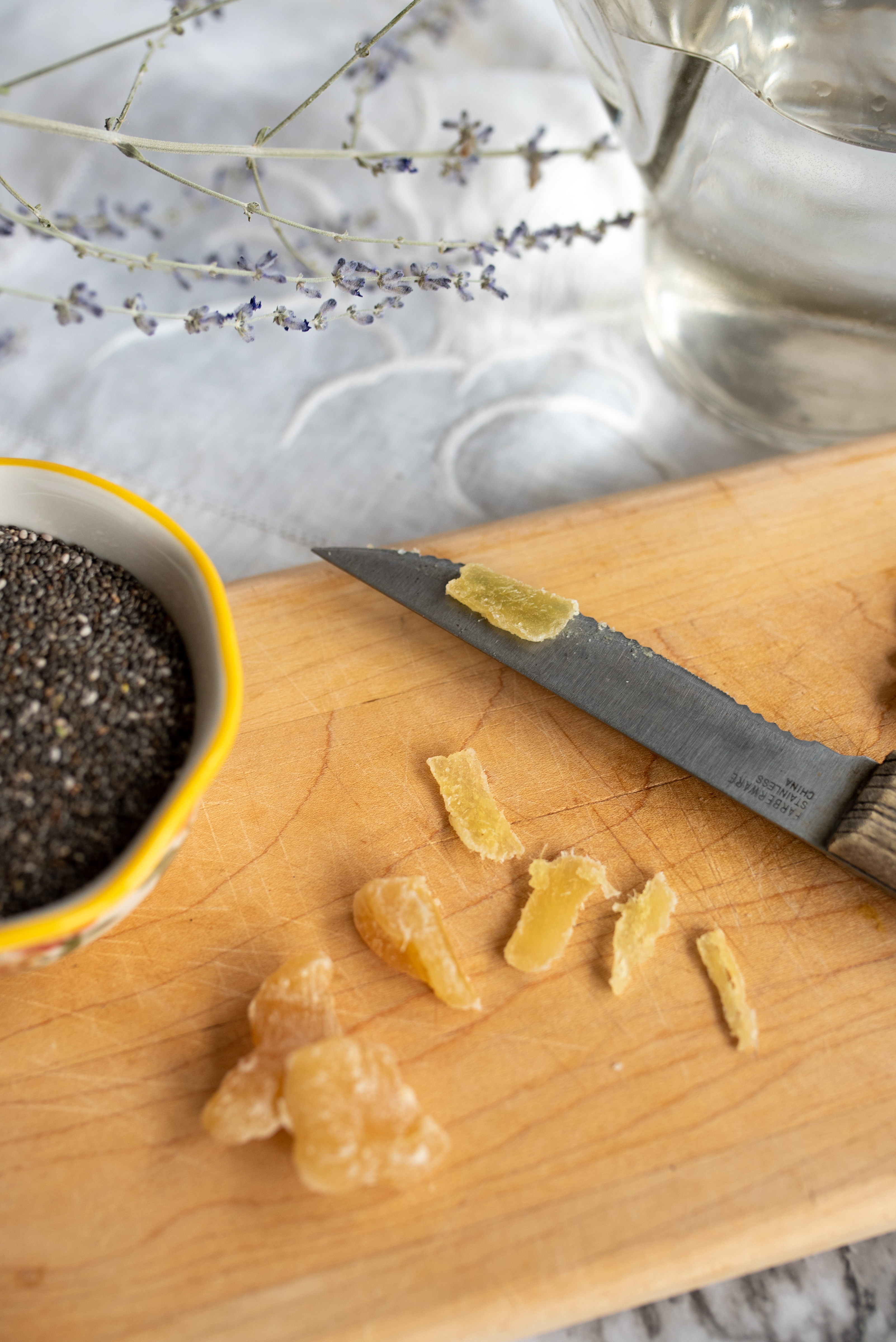 a cutting board with a knife, chopped fruit, and a small bowl on it