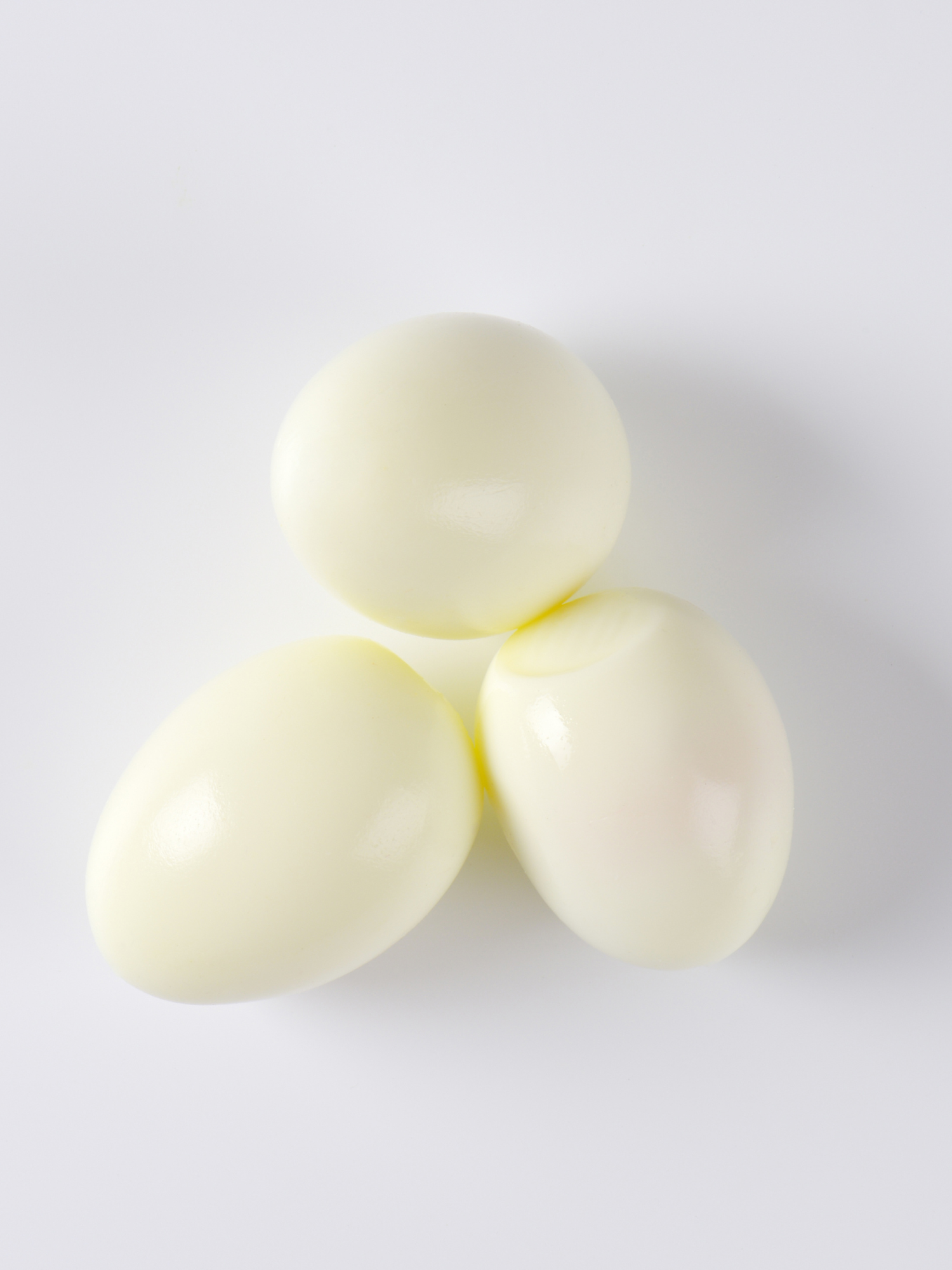 3 peeled hard boiled eggs peeled and on a white surface