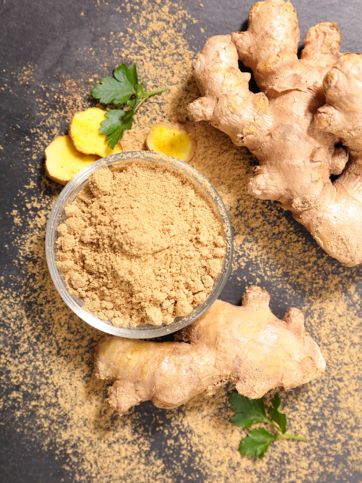 ginger roots laying on a table next to a bowl of brown powder