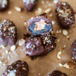 almond butter stuffed dates lined up on brown paper and sprinkled with crushed almonds