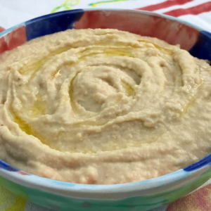 a big colorful bowl of two ingredient hummus on a coloful tablecloth 