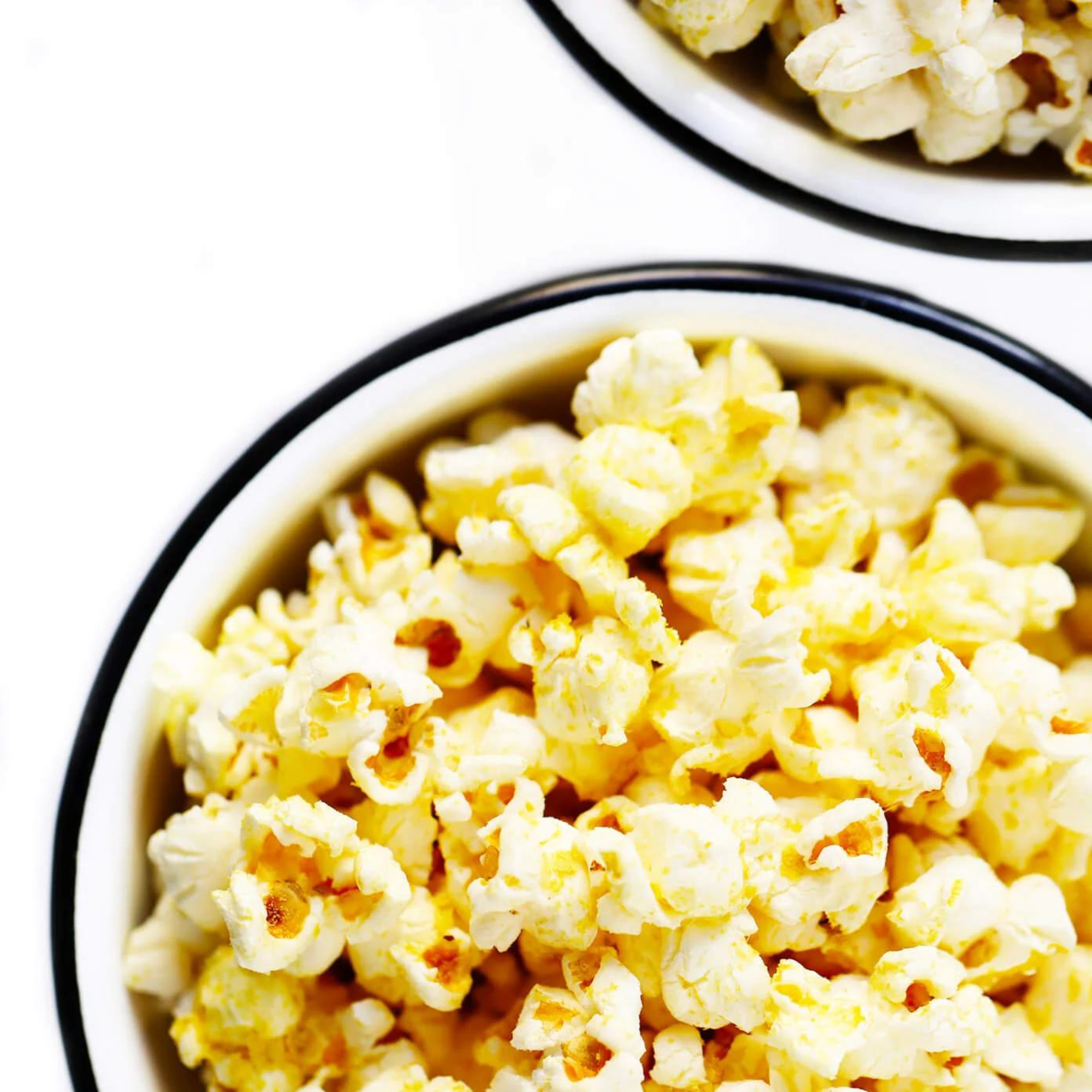 white cup full of nutritional yeast popcorn on a white background