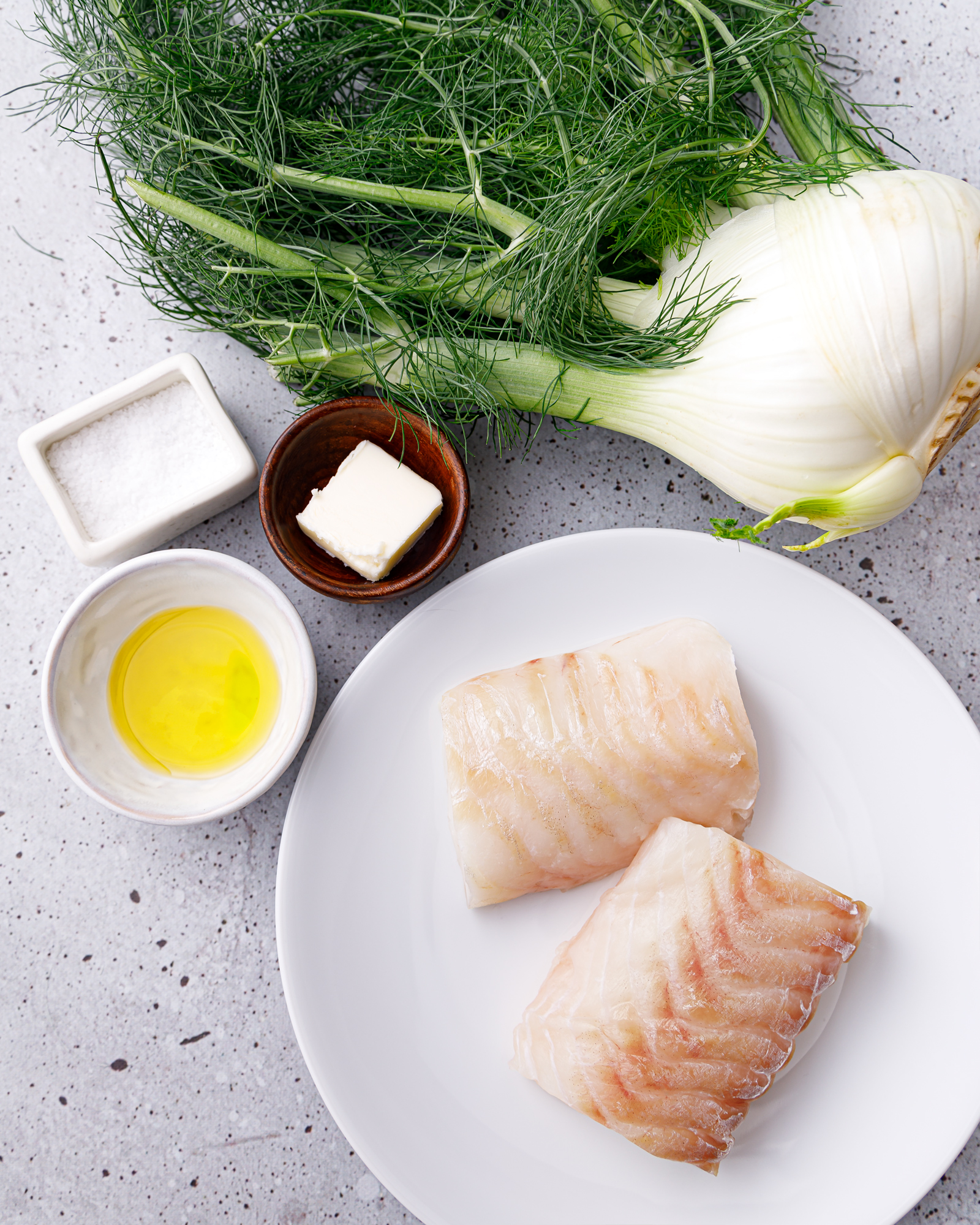 a plate with uncooked sea bass surrounded by a fennel bulb