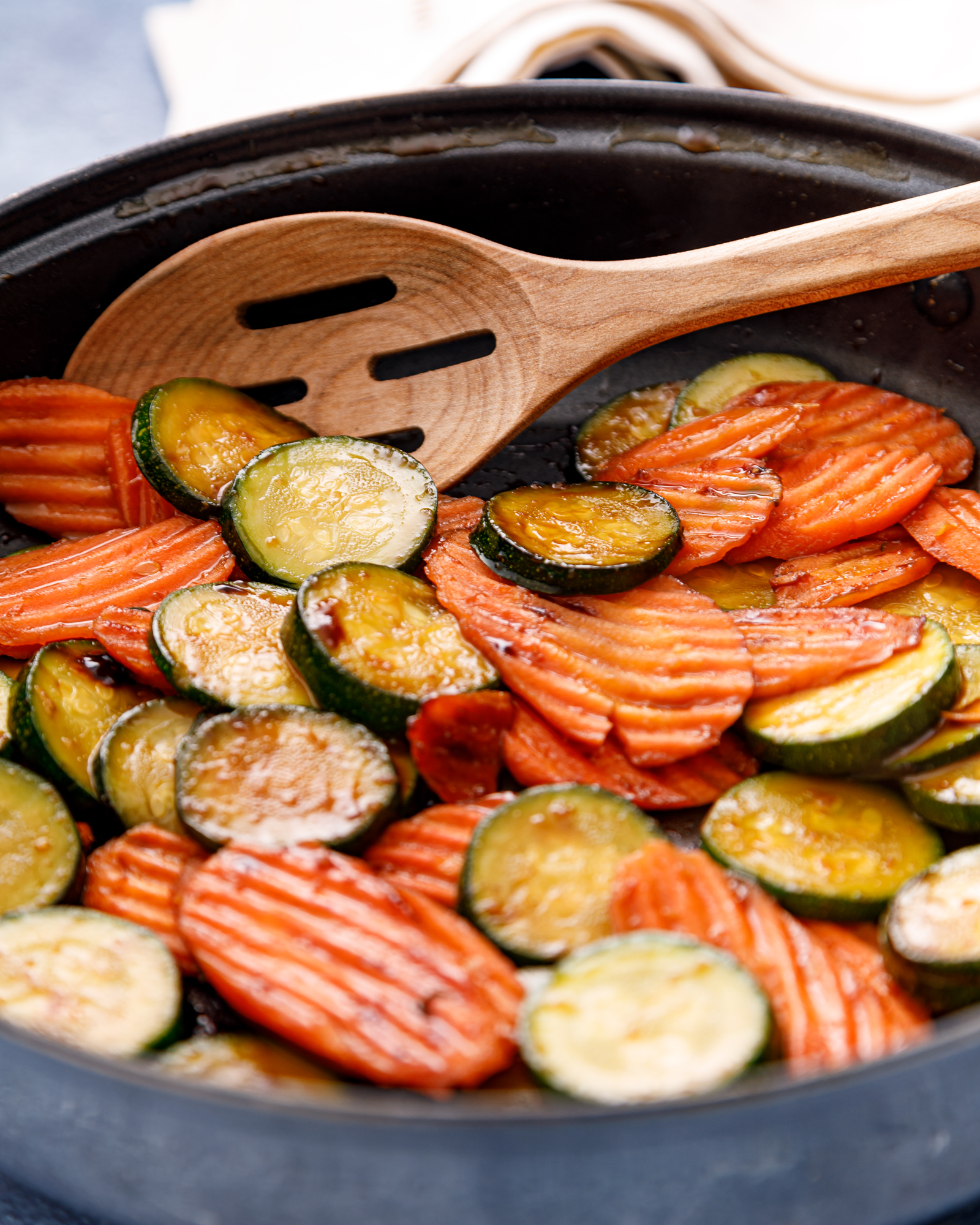 a skillet of cooked vegetables and a wooden spoon
