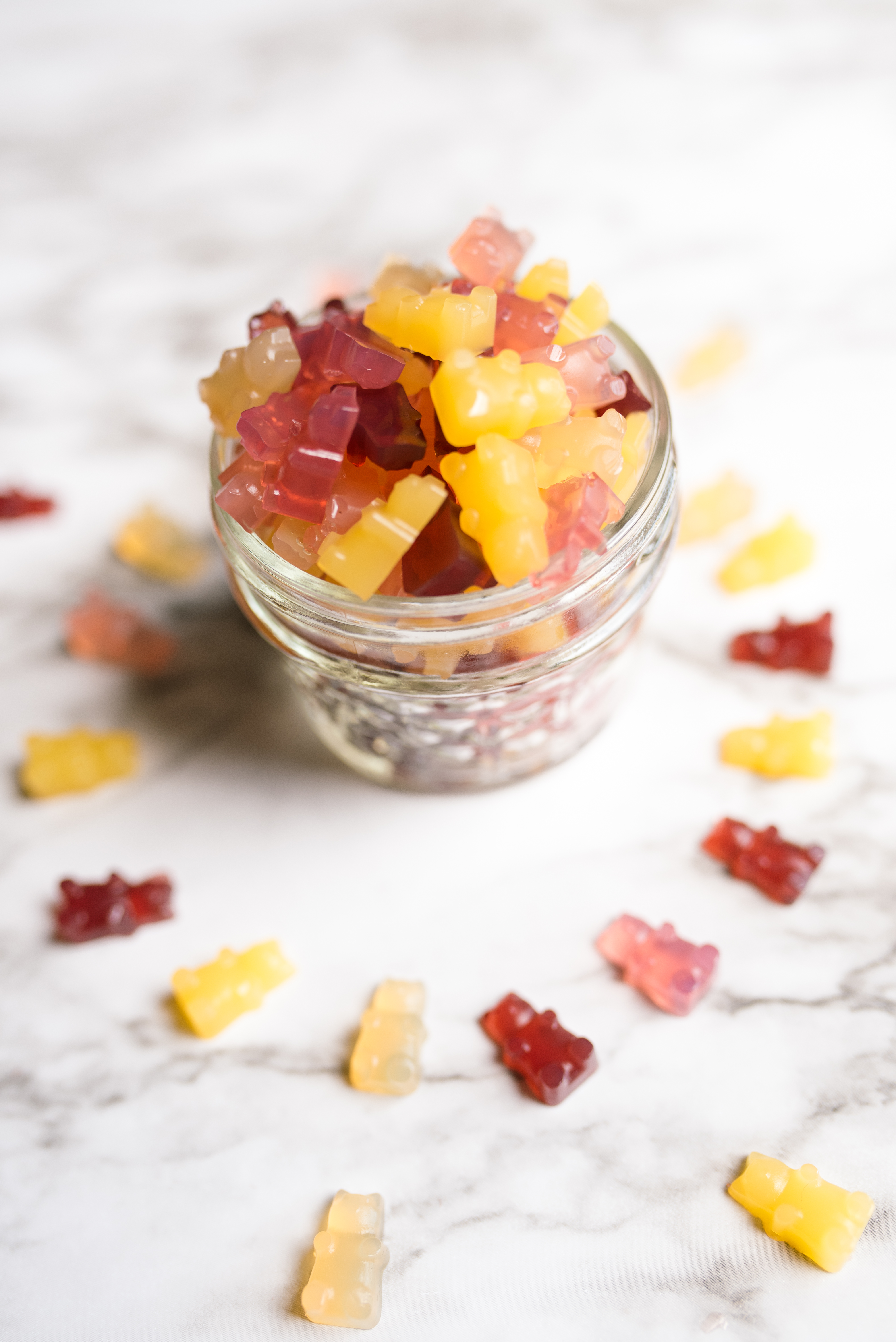 a small jar filled with multi-colored vegan gummy bears with a circle of gummy bears around the base of the jar