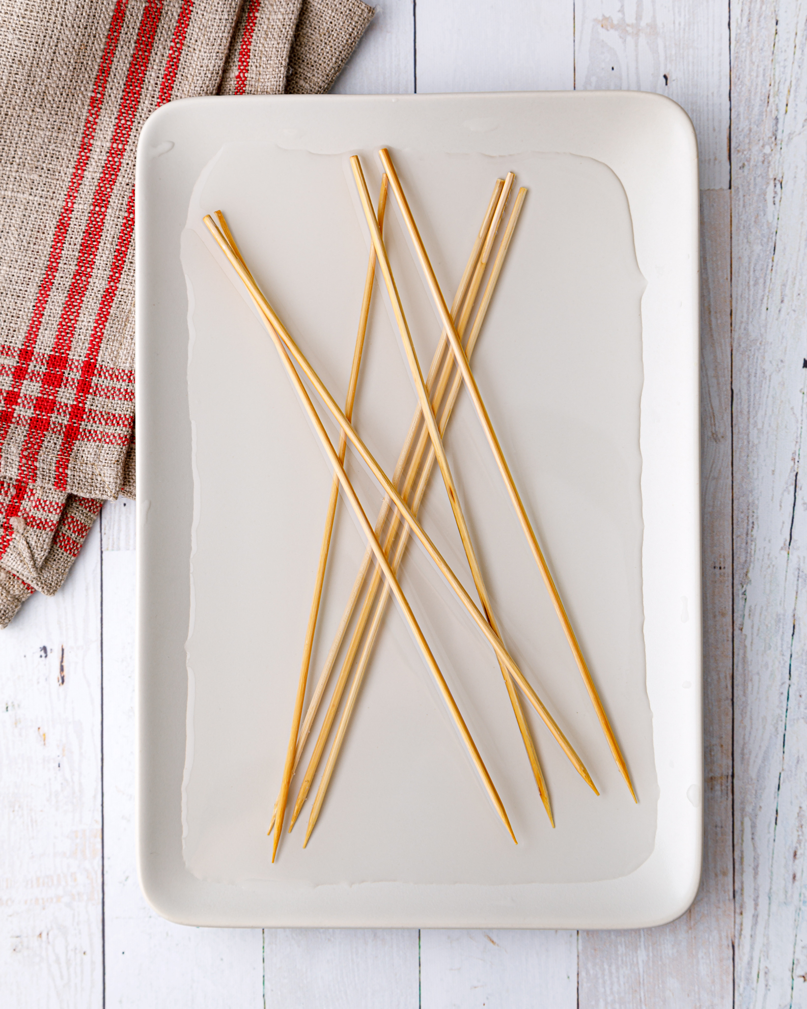 bamboo kebob skewers soaking in some water on a small white tray