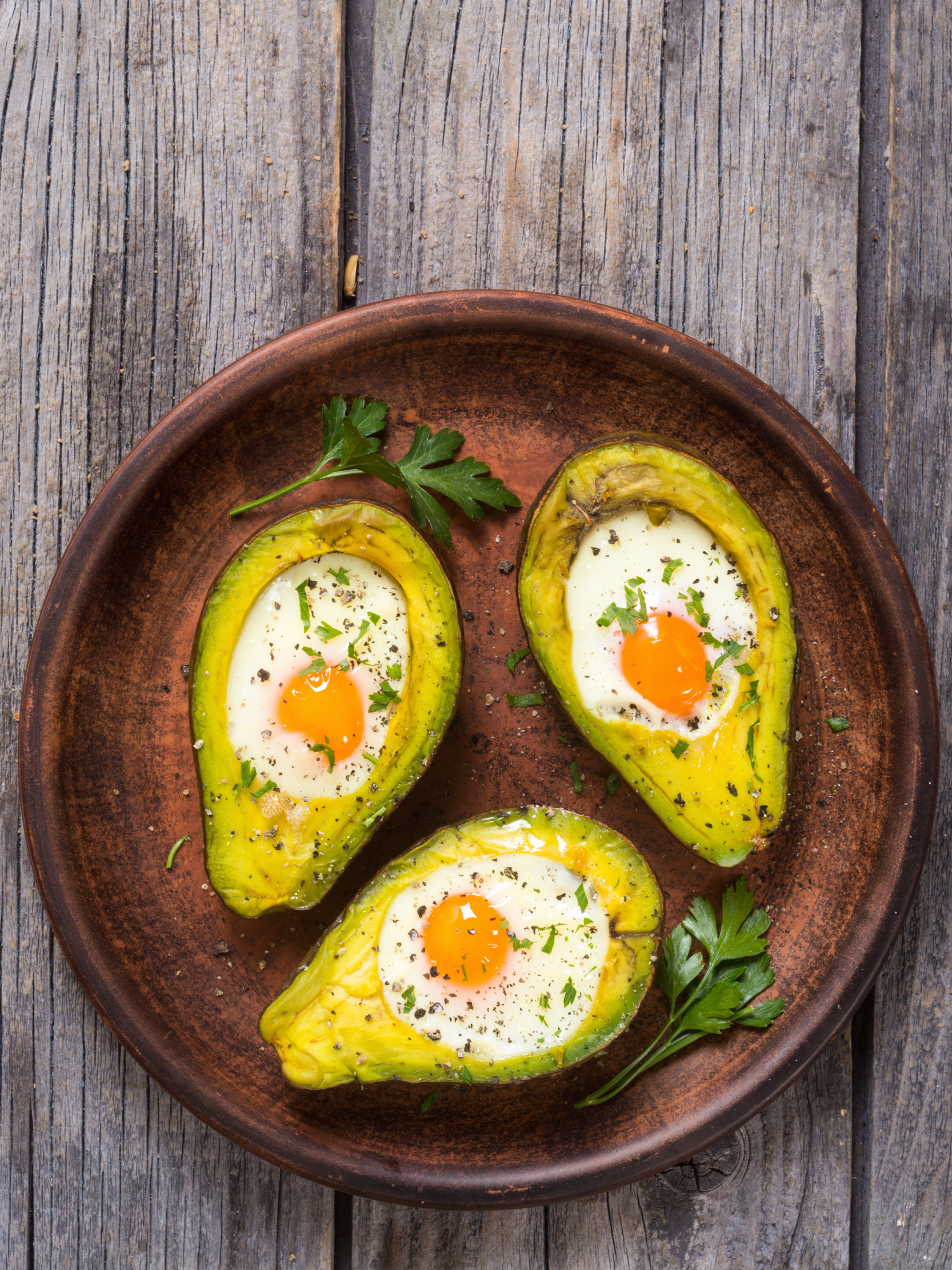 a brown plate with poached egg filled avocado's