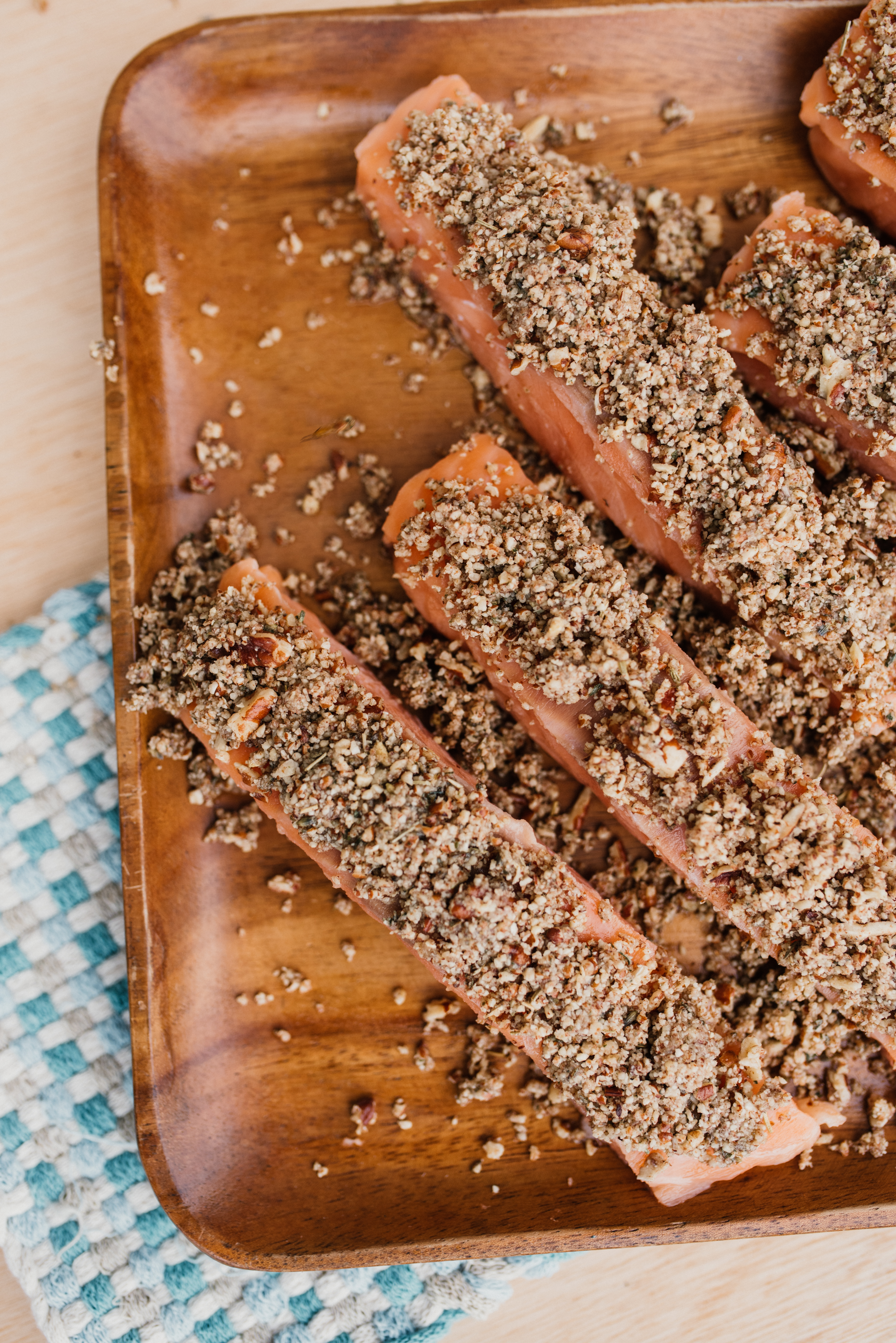 a wooden platter with salmon fillets that have been covered in the honey pecan crust