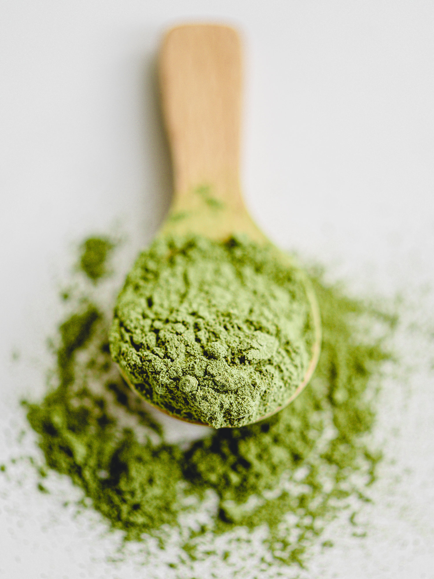 a wooden spoon filled with green matcha powder