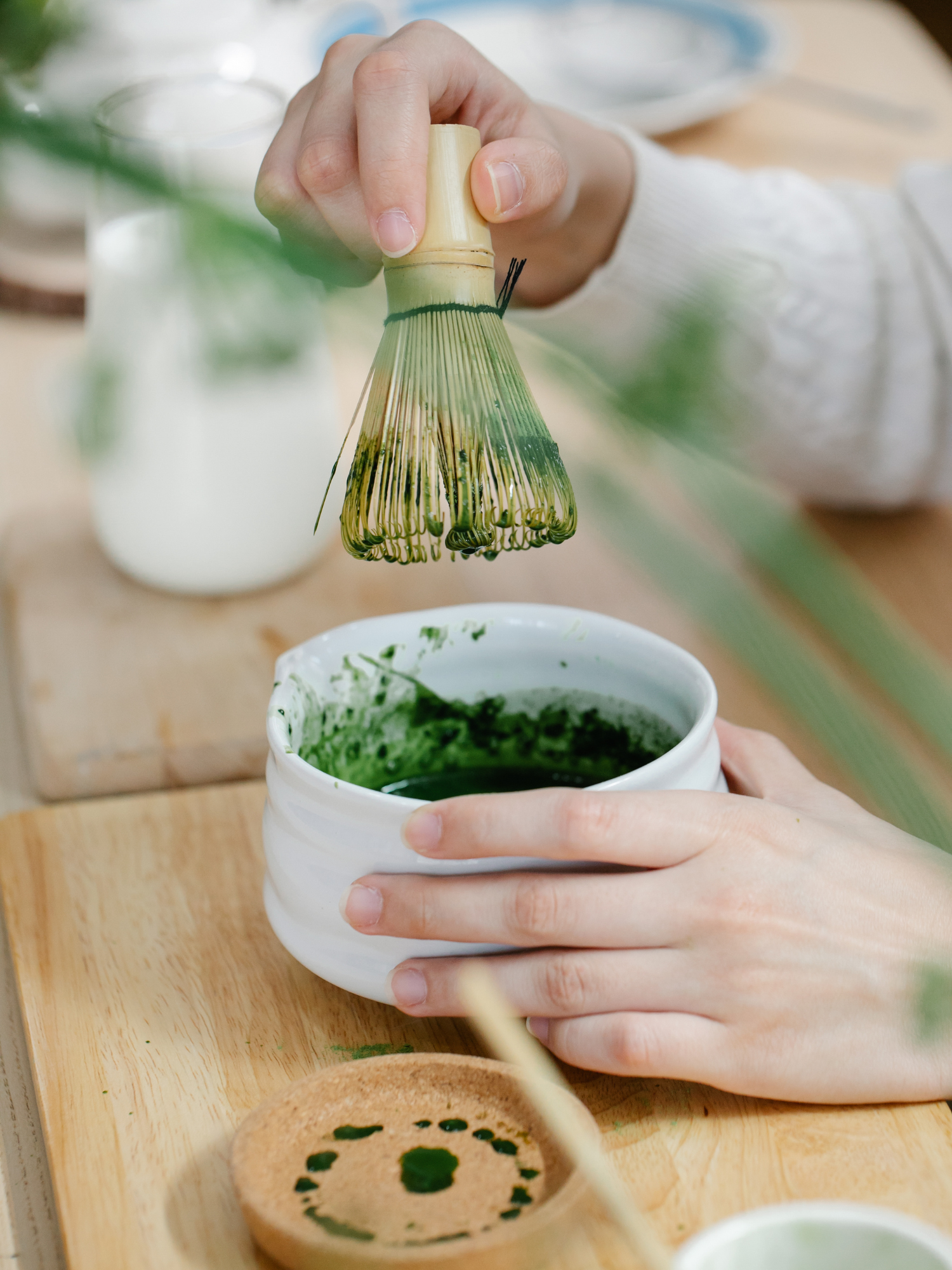 a woman holding a whisk and a cup of matcha tea