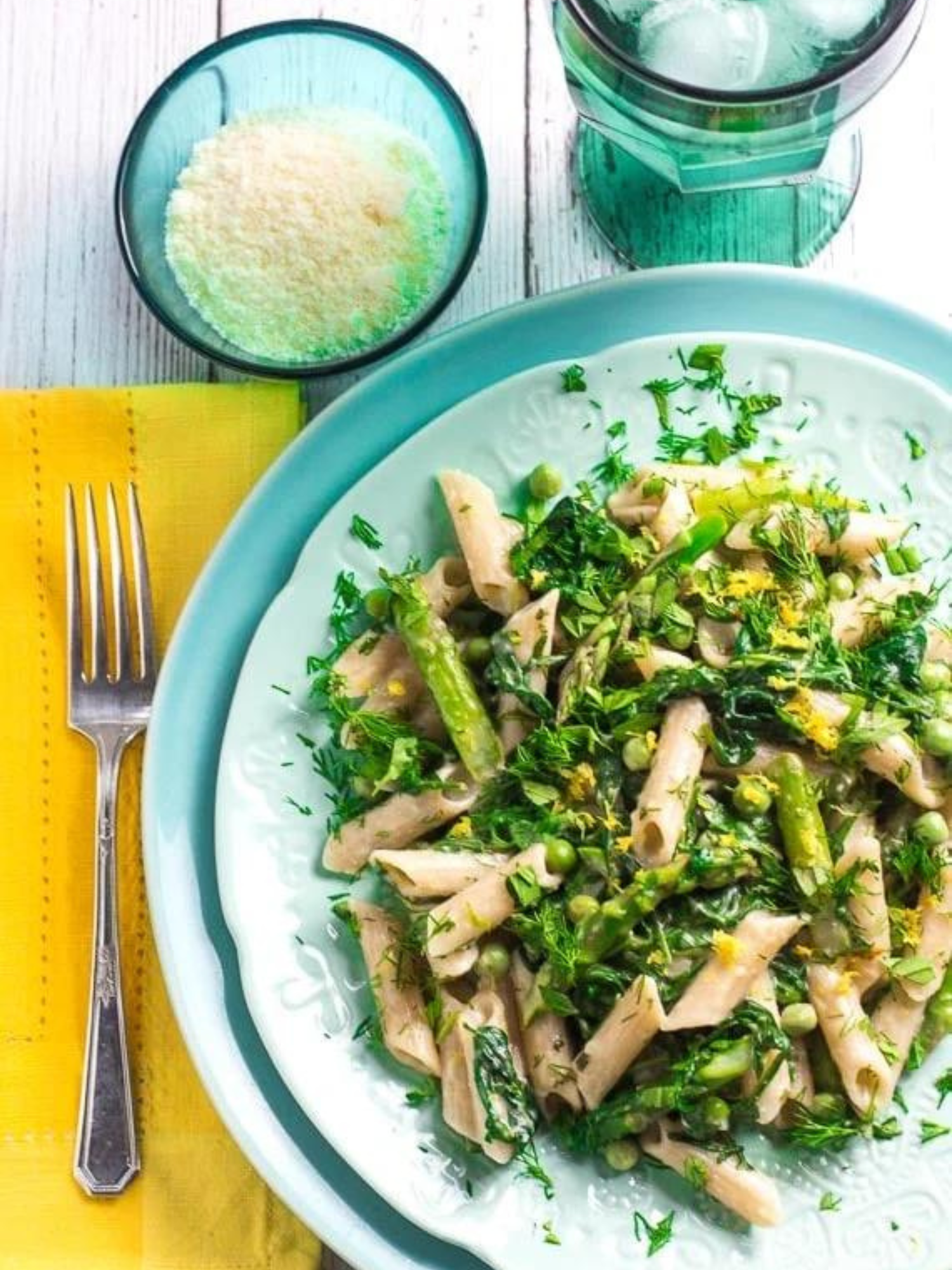 a blue plate of low Fodmap Pasta Primavera on a table with a yellow napkin and fork