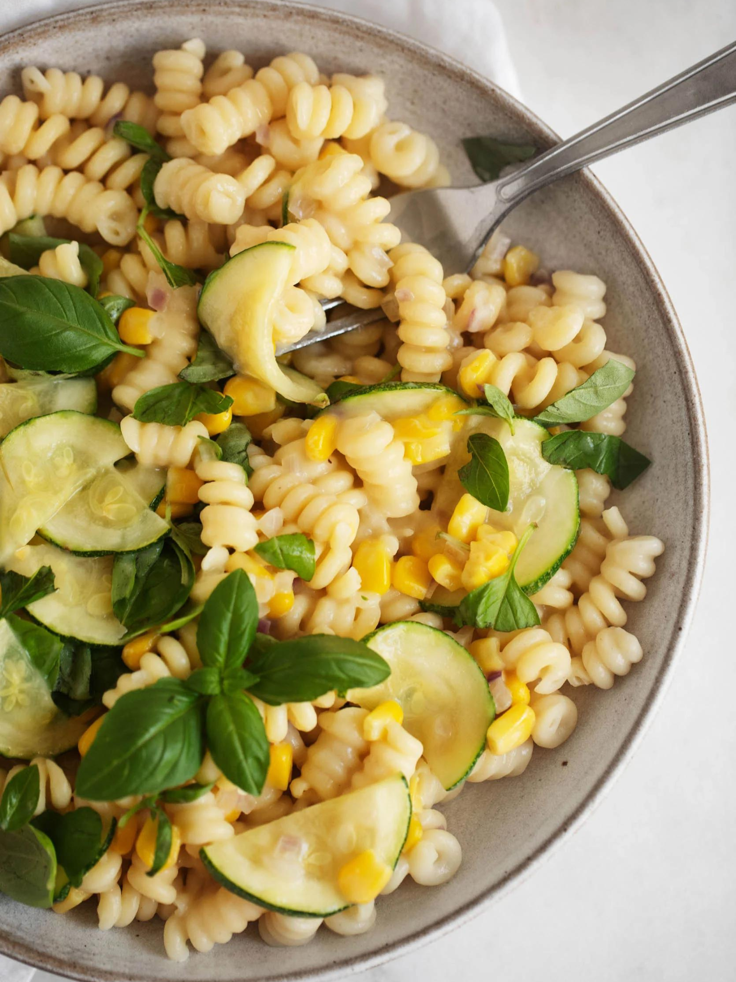 a big bowl of easy healthy Creamy Zucchini Corn Pasta with a fork