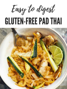 a big white bowl of gluten free pad thia with a fork and a lime wedge