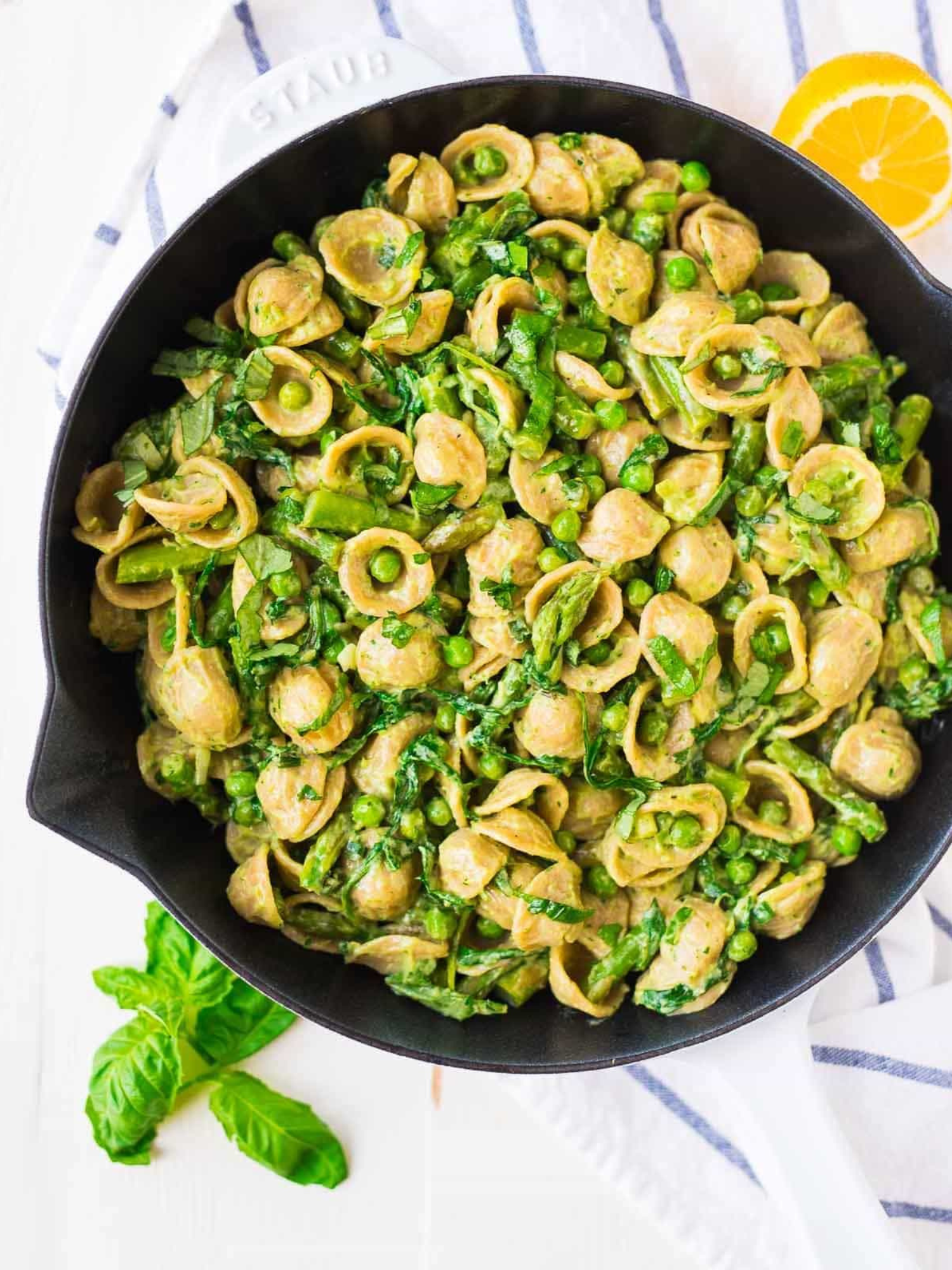 an iron skillet of avacado pasta with Fresh asparagus, herbs, green onions, and arugula make the dish feel light and bright.