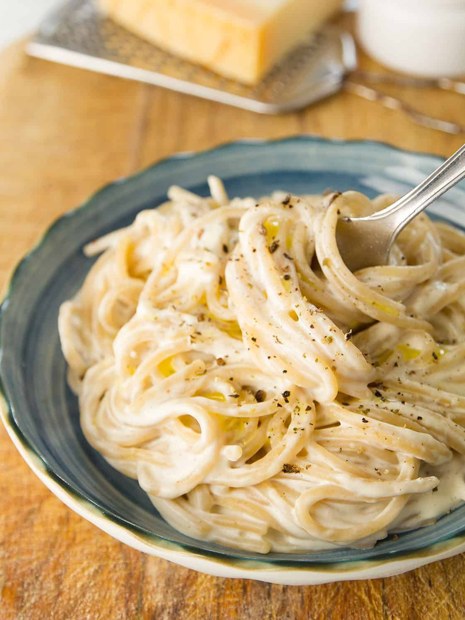 a big bowl of 10 minute cream cheese pasta sitting on a table with cheese sitting behind it.