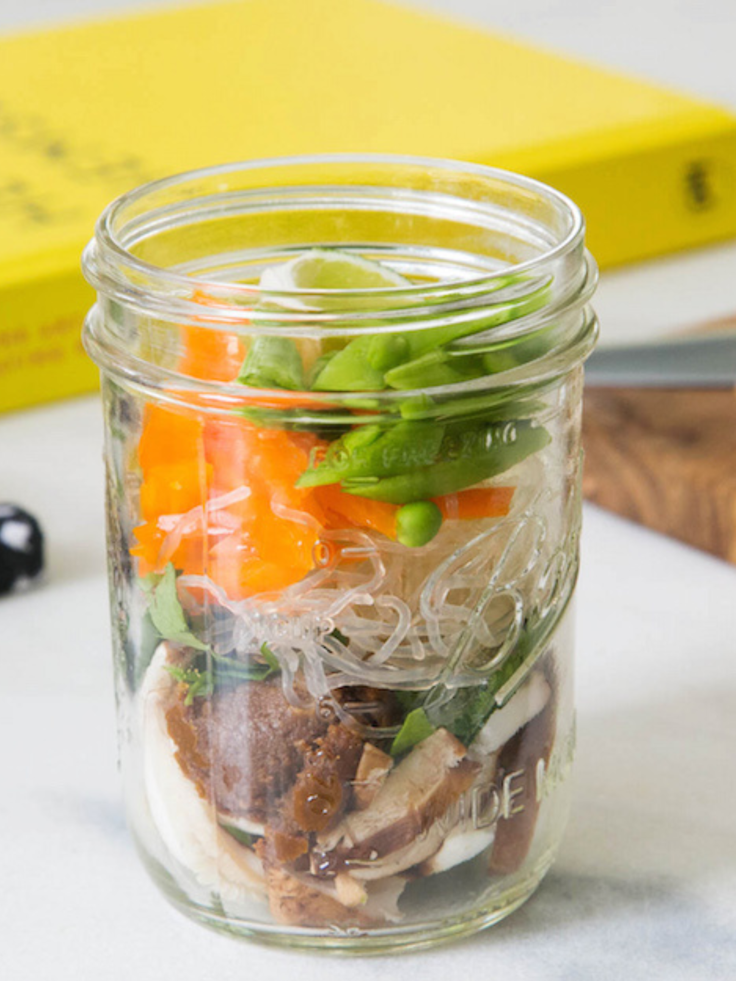 a mason jar layered with miso, kelp noodles, carrots, mushrooms and fresh herbs